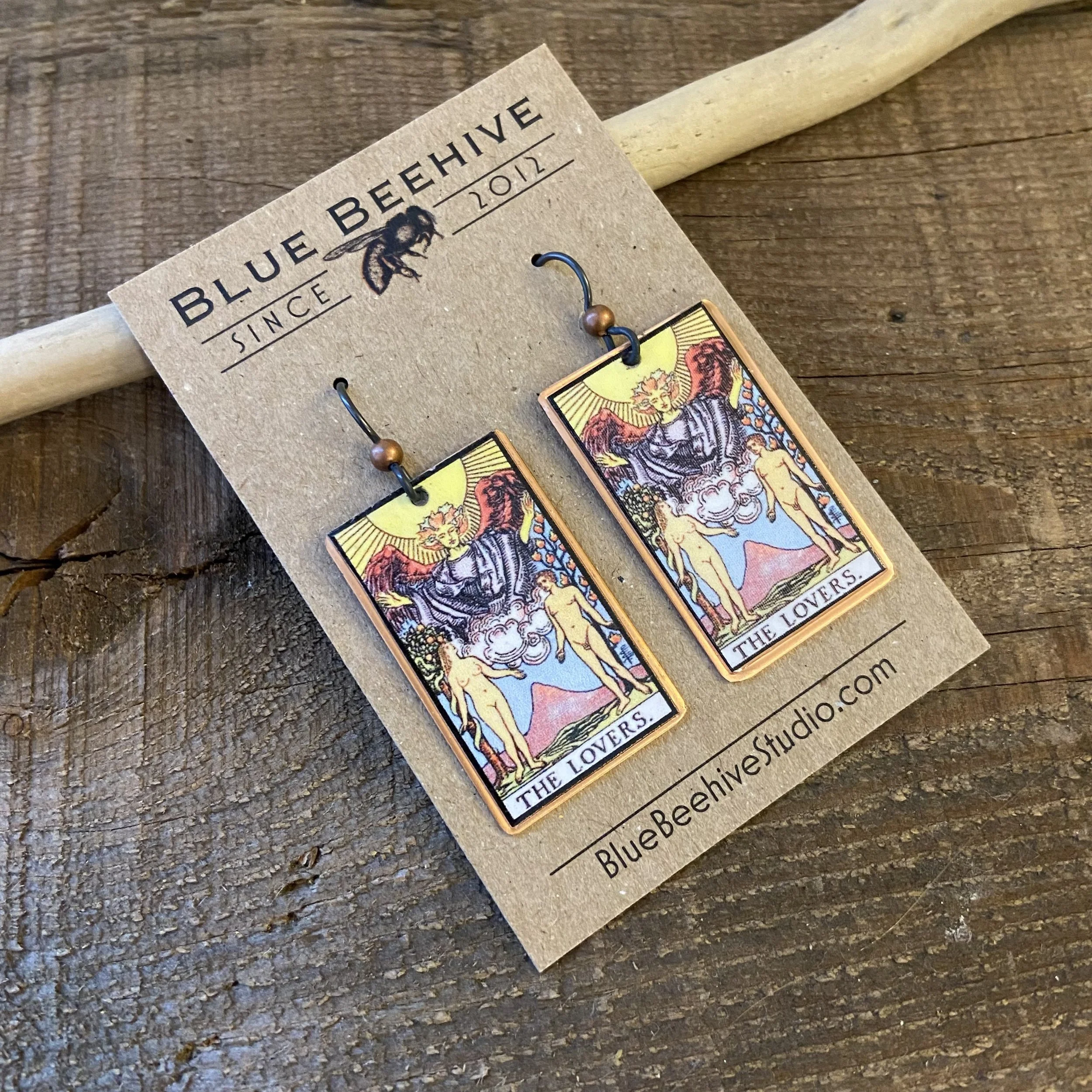 Picture of rectangular earrings of The Lovers tarot card from the Rider-Waite Deck. Ear wires are black niobium with small copper balls.