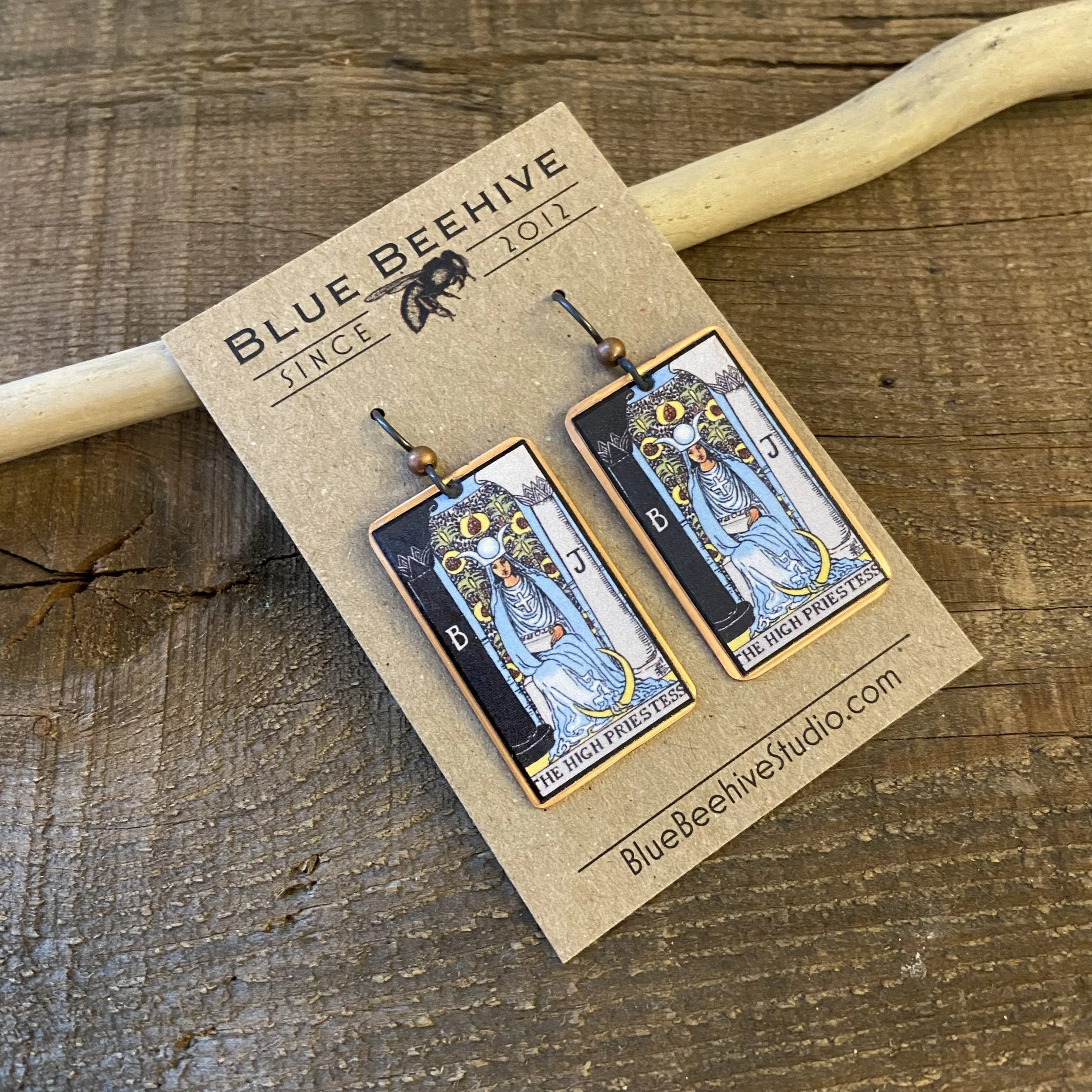 Picture of rectangular earrings of The High Priestess tarot card from the Rider-Waite Deck. Ear wires are black niobium with small copper balls.
