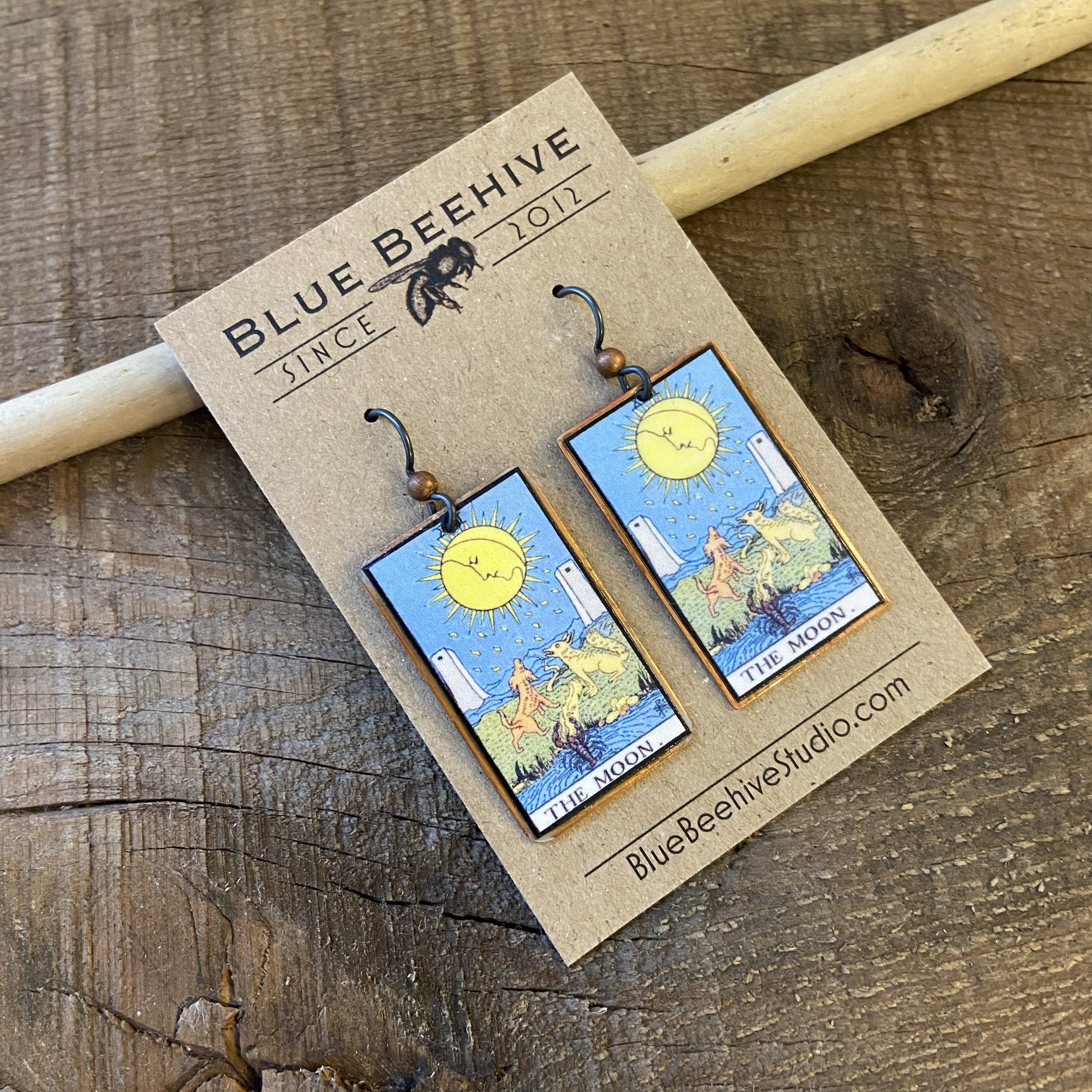 Picture of rectangular earrings of The Moon tarot card from the Rider-Waite Deck. Ear wires are black niobium with small copper balls.