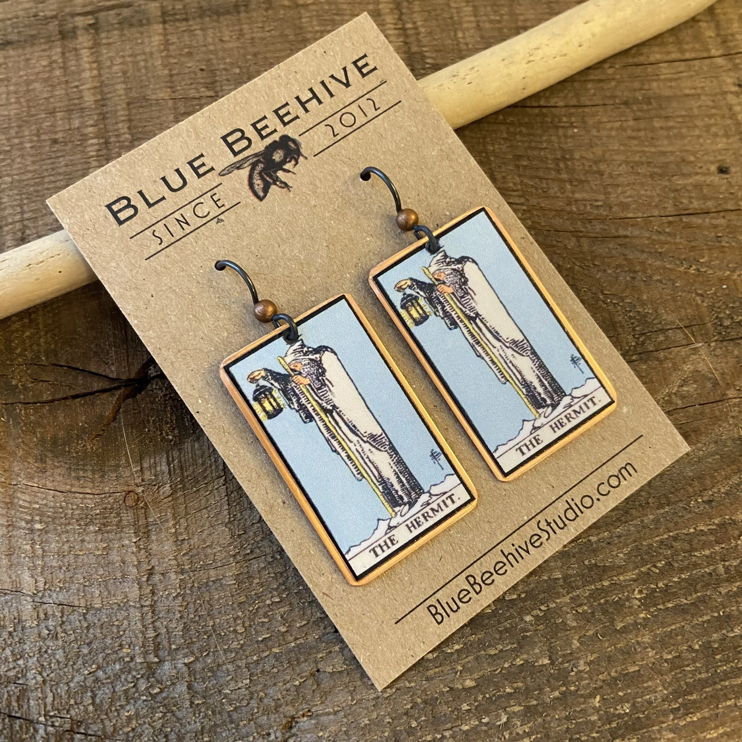 Picture of rectangular earrings of The Hermit tarot card from the Rider-Waite Deck. Ear wires are black niobium with small copper balls.