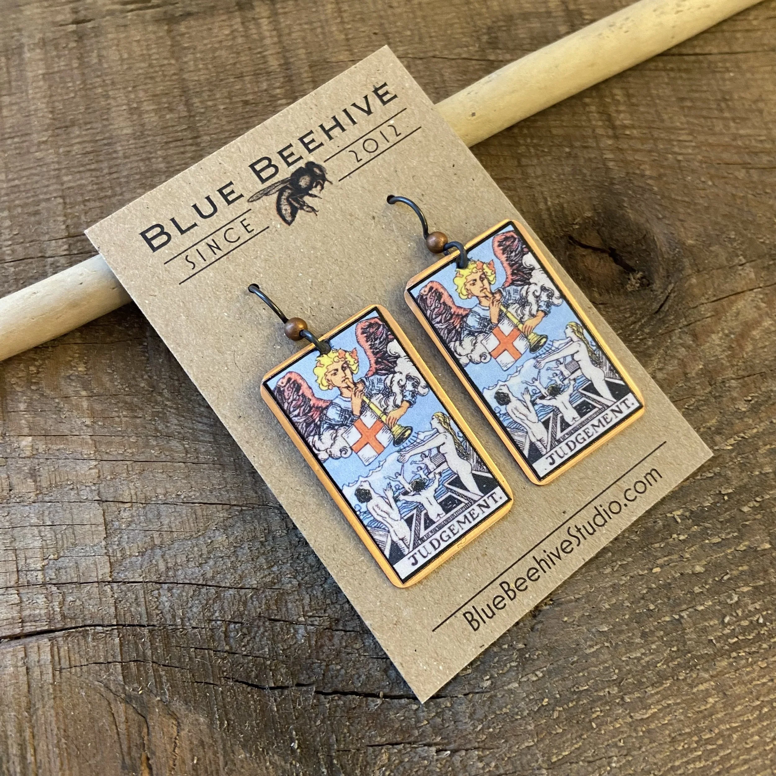 Picture of rectangular earrings of the Judgement tarot card from the Rider-Waite Deck. Ear wires are black niobium with small copper balls.