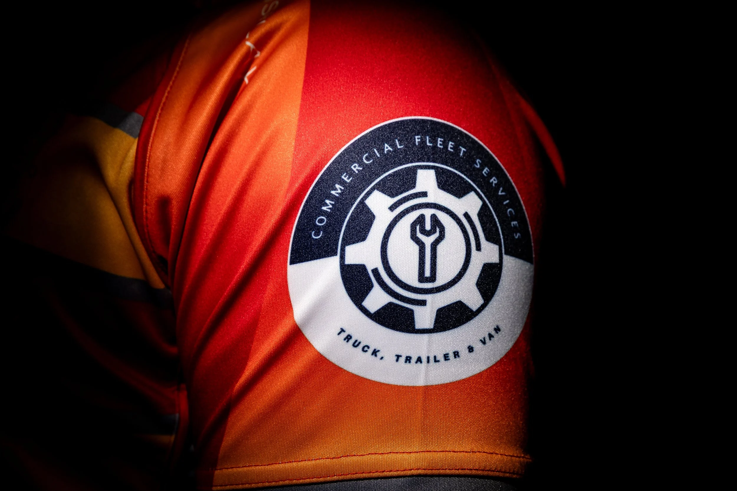 A close up photo of a logo of a sponsor on a rugby top shoulder with a black background