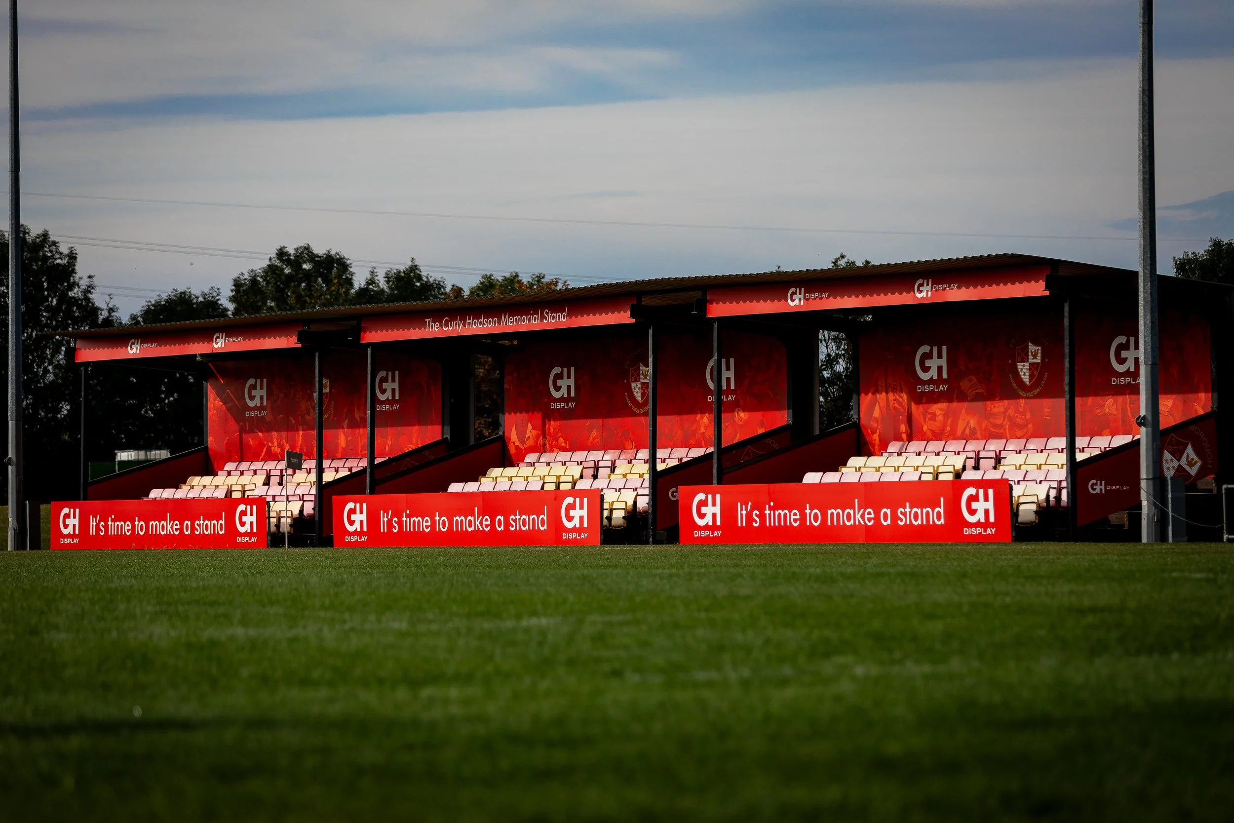 A product photo of a newly wrapped stand by GH Display across the rugby pitch as the sun rises