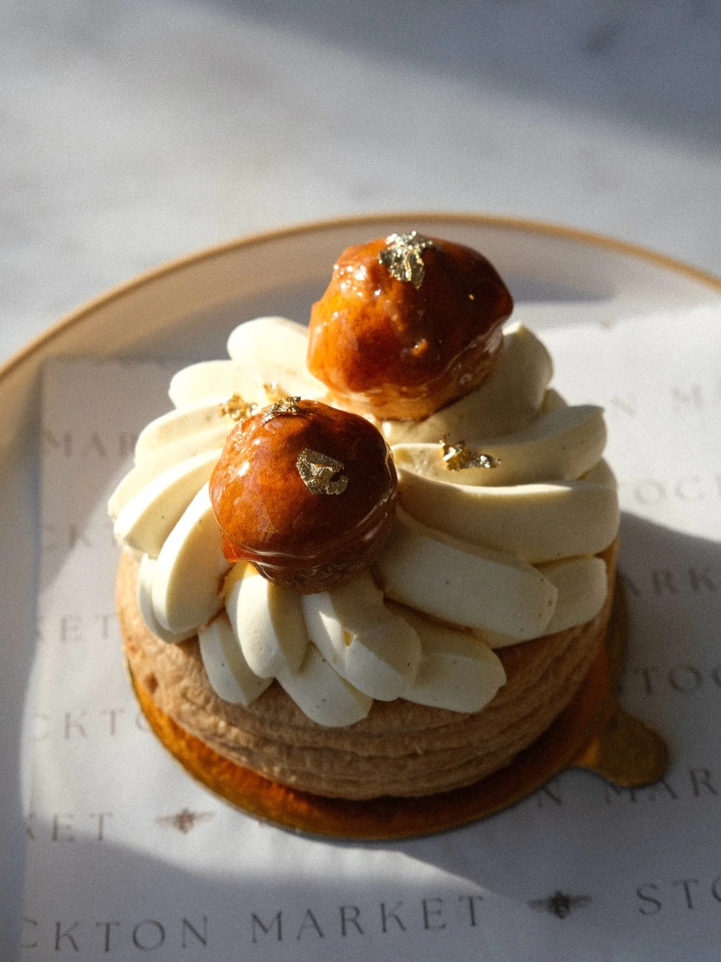 Chef Guada&rsquo;s St. Honor&eacute; cake features a puff pastry base, topped with vanilla pastry cream, and decorated with two caramel-glazed cream puffs. Limited quantities and made special for the weekends 💌