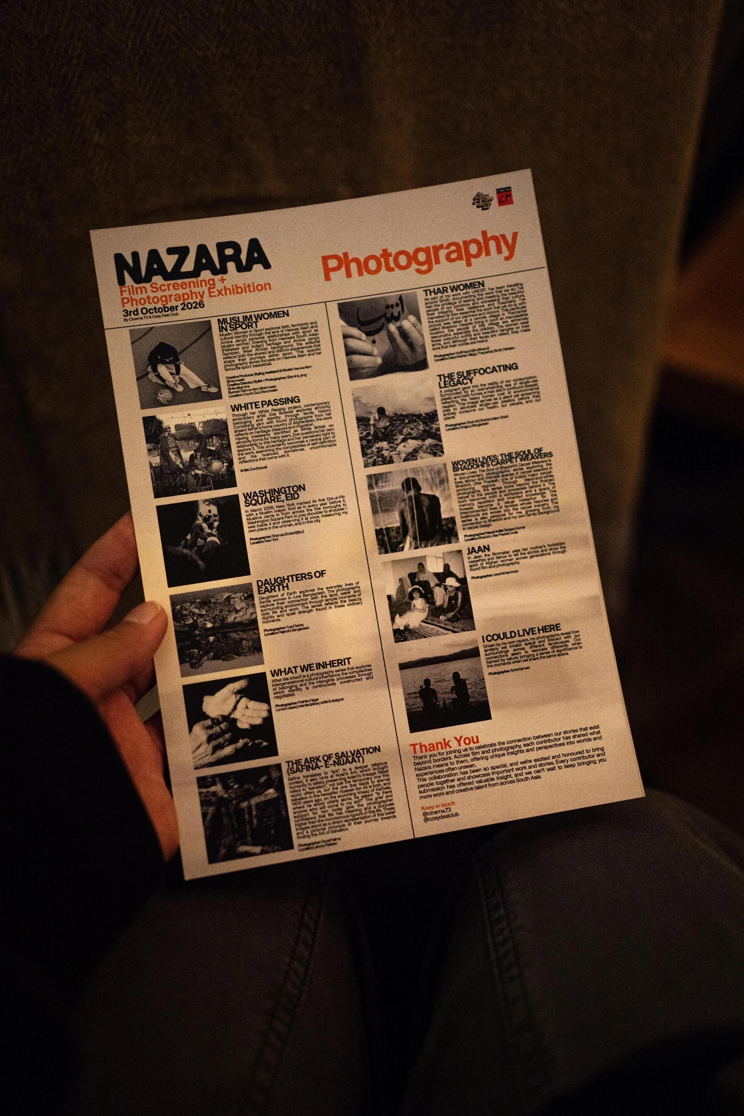 A person holding a printed flyer with a white background and black and orange text, featuring articles and images related to a photography exhibition event called NAZARA.