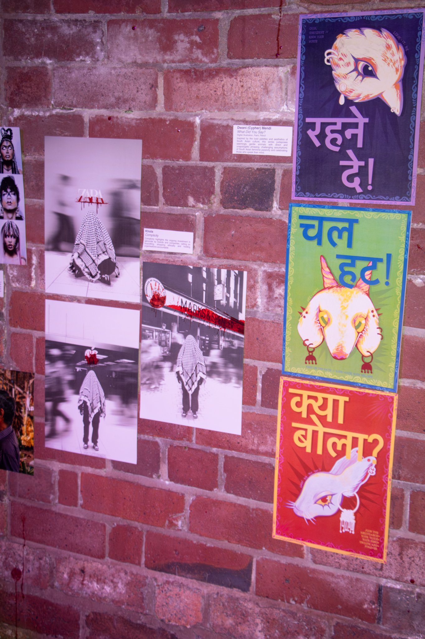 Photo of a brick wall with various posters and photographs displayed.