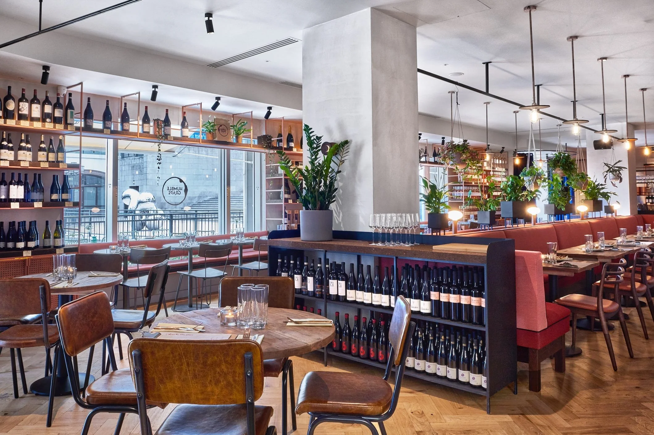 The main dining room at Humble Grape Canary Wharf with wine displays and set tables.