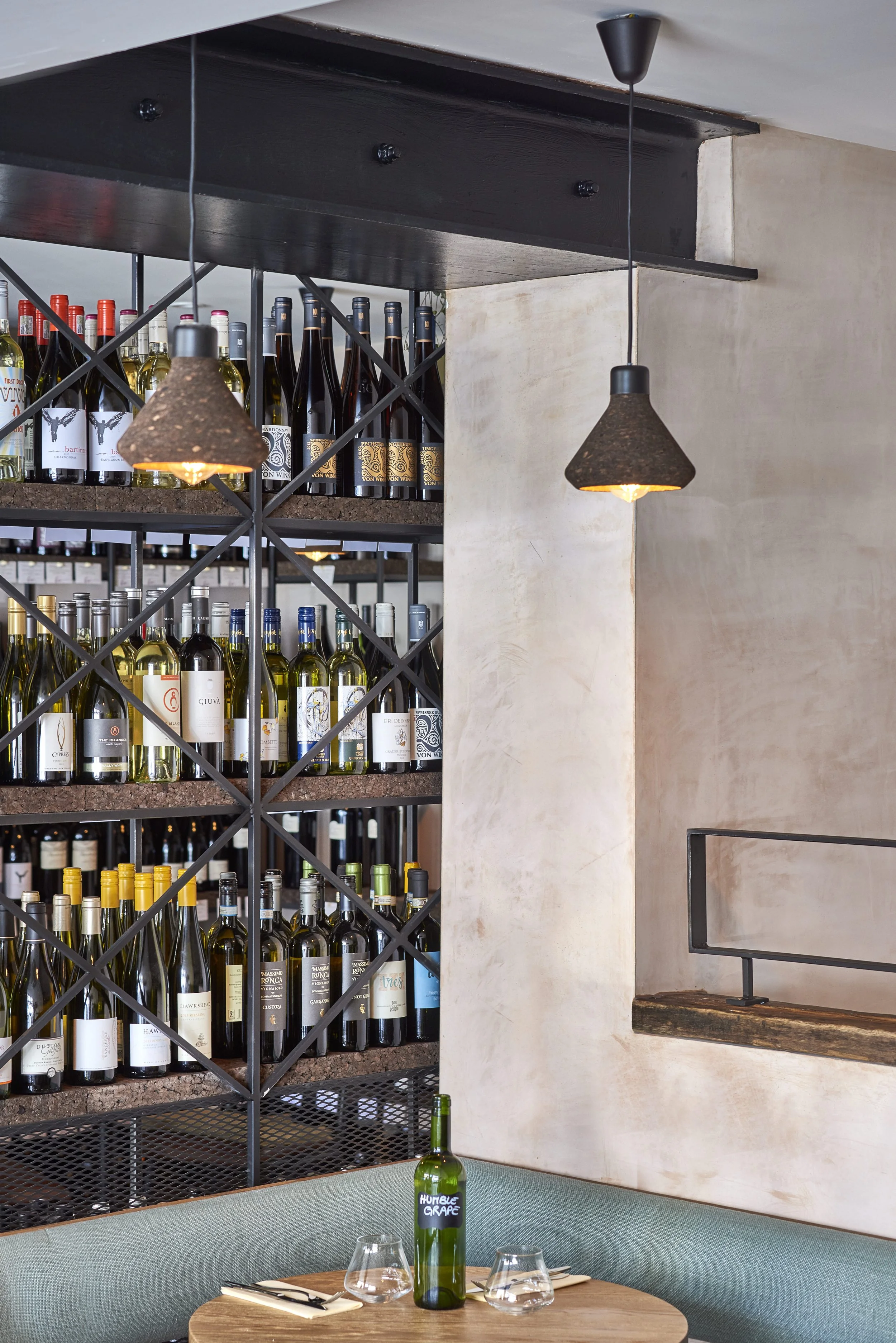 Wine shelving and a branded Humble Grape bottle on a table inside Humble Grape Islington.