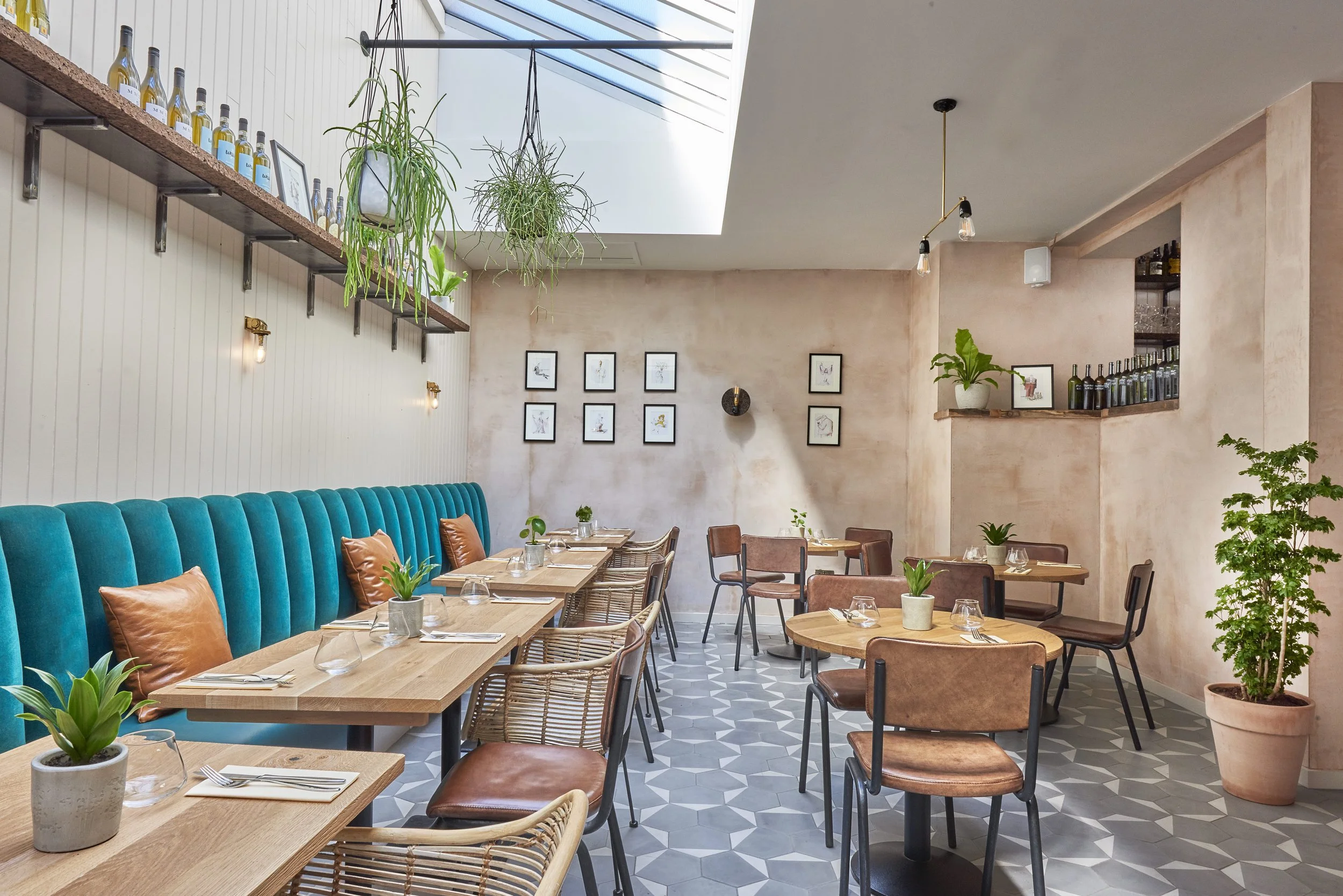 The Humble Grape Islington dining room, with teal banquette seating, set tables and hanging plants.