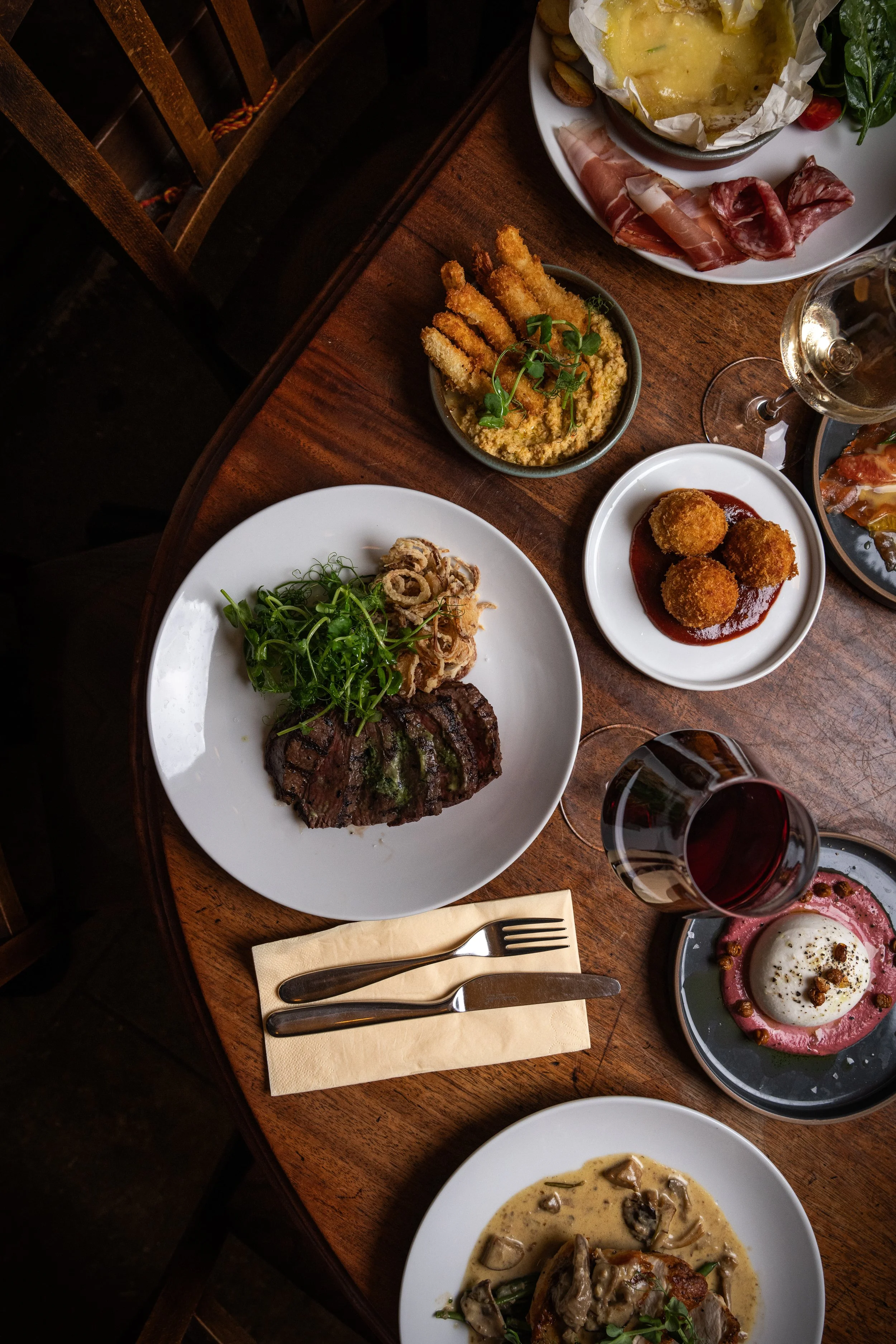 Sharing plates and glasses of wine on a wooden table inside Humble Grape Bow Lane
