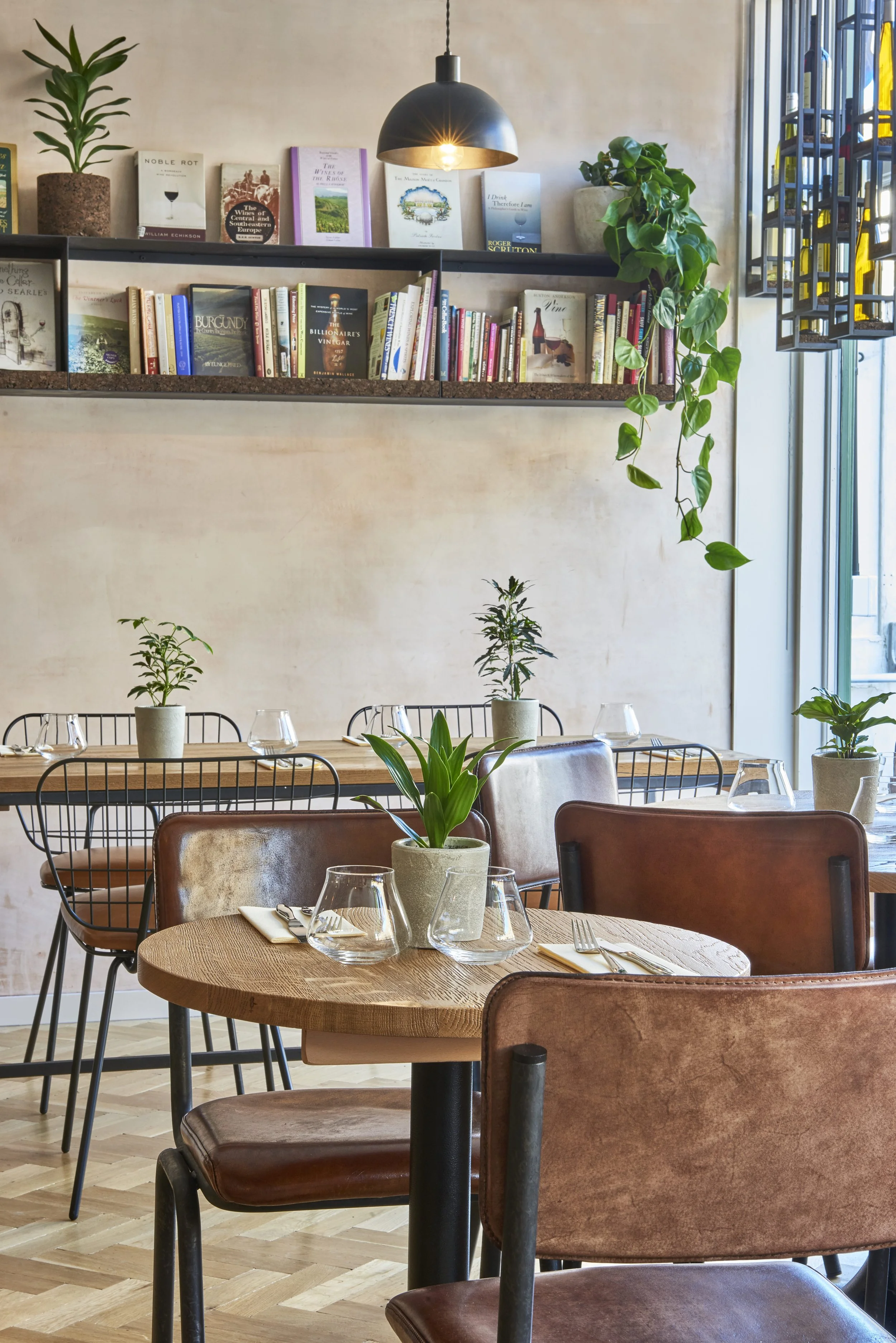 A dining table and bookshelf inside Humble Grape Islington, wine and food books on display