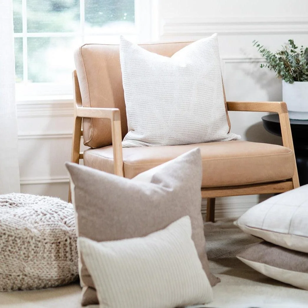 Cozy neutral therapy chair with organic textured pillows and soft natural light in calming office space
