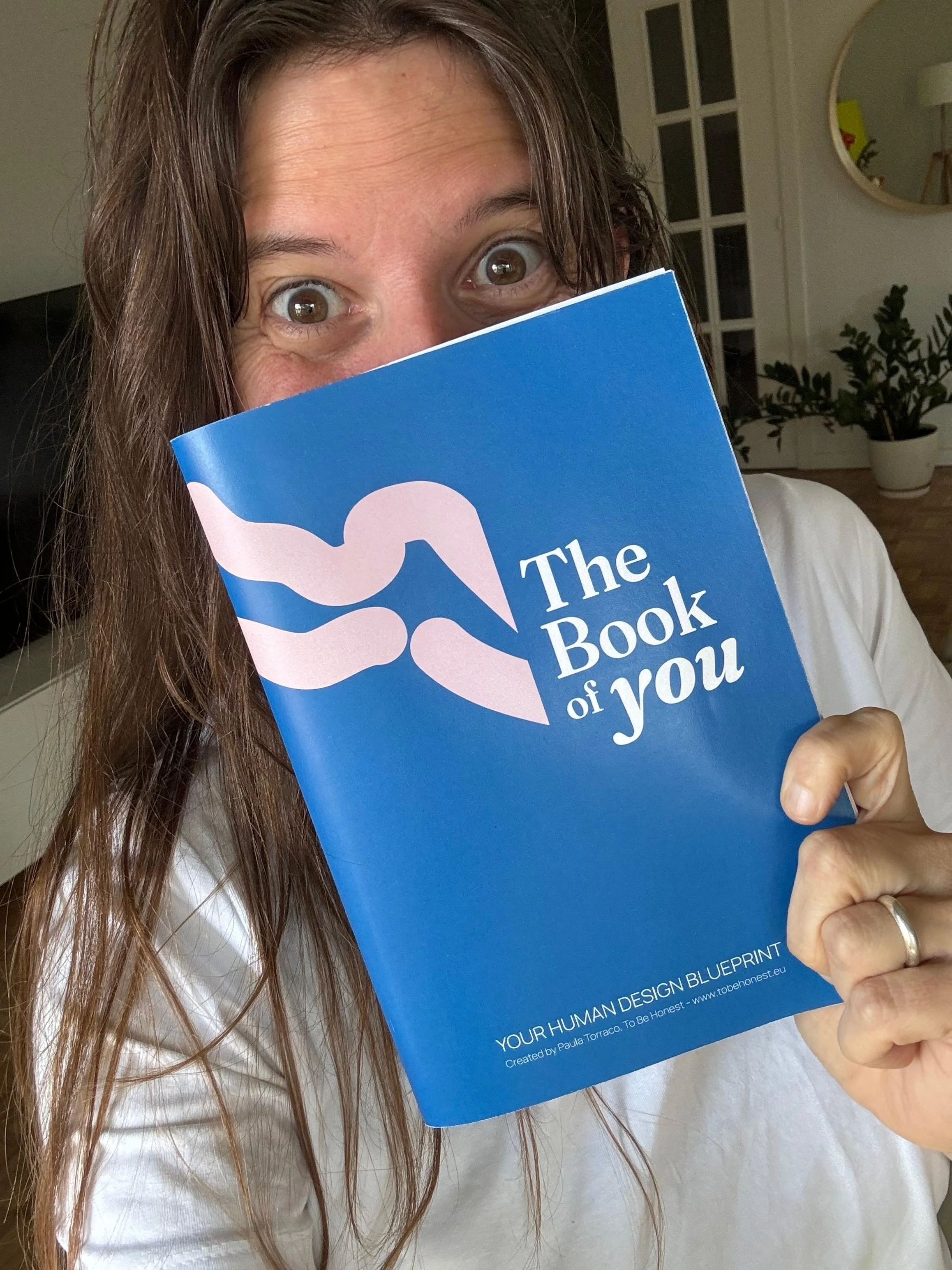 Client holding her Book of You - a personalised 50+ page Human Design blueprint. Understand how you're wired to live, decide, and lead. Written by Paula Torraco. Available in English and Spanish.