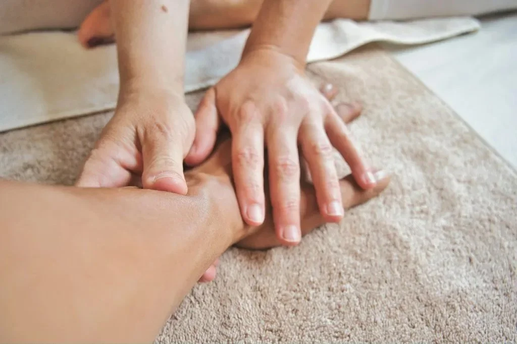 Close-up of hands performing deep tissue massage on a forearm, symbolizing healing touch in trauma-informed bodywork.