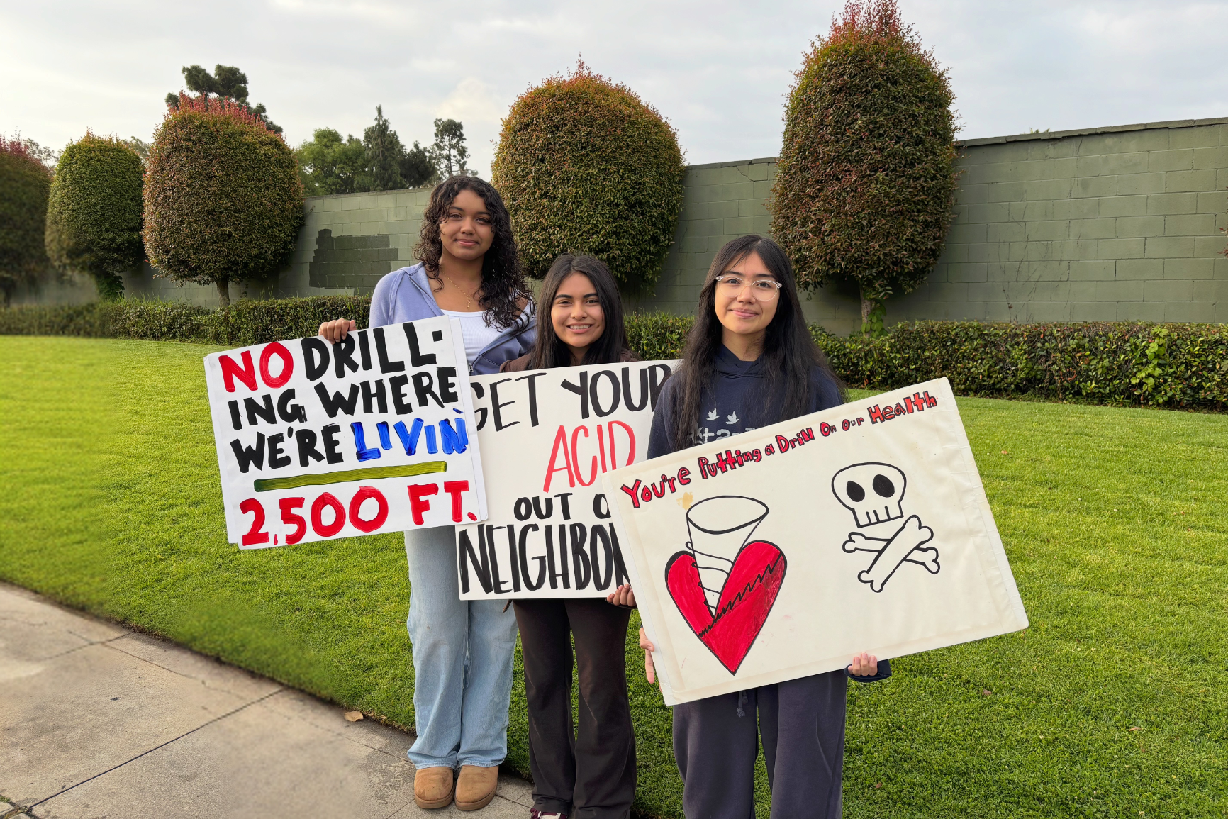 Teens standing in front of the Murphy Drill Site in South Los Angeles protesting against planned acid maintenance work