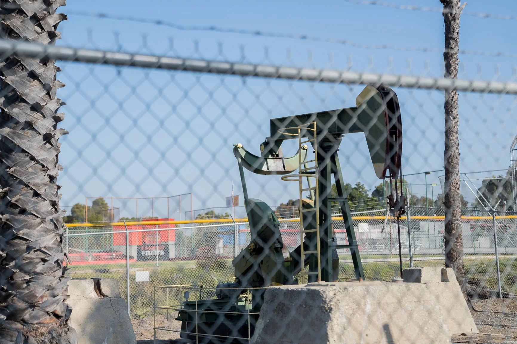 Oil derrick behind a fence, next to a school in the Wilmington neighborhood in Los Angeles.