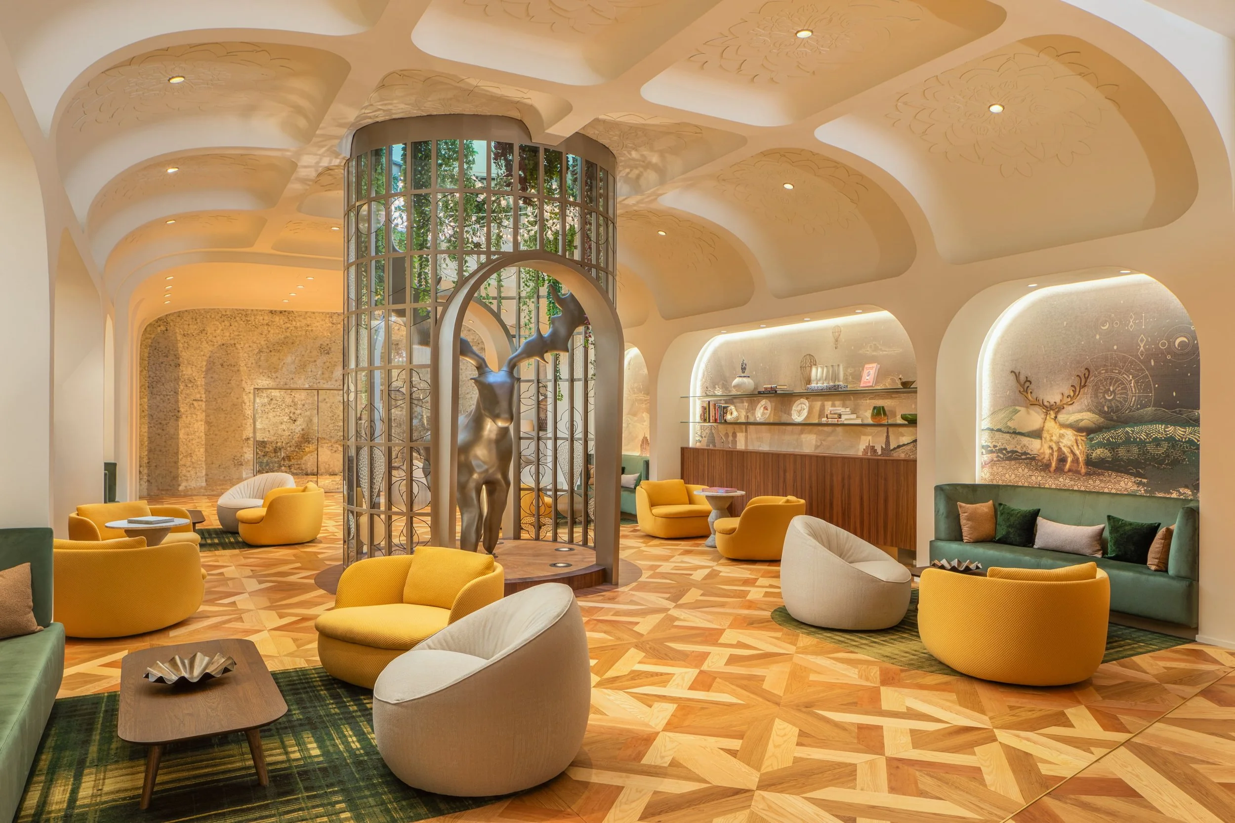 Moderner Lounge-Bereich mit bunten Sesseln, Skulptur eines Rehs und dekorativem Holzfußboden.