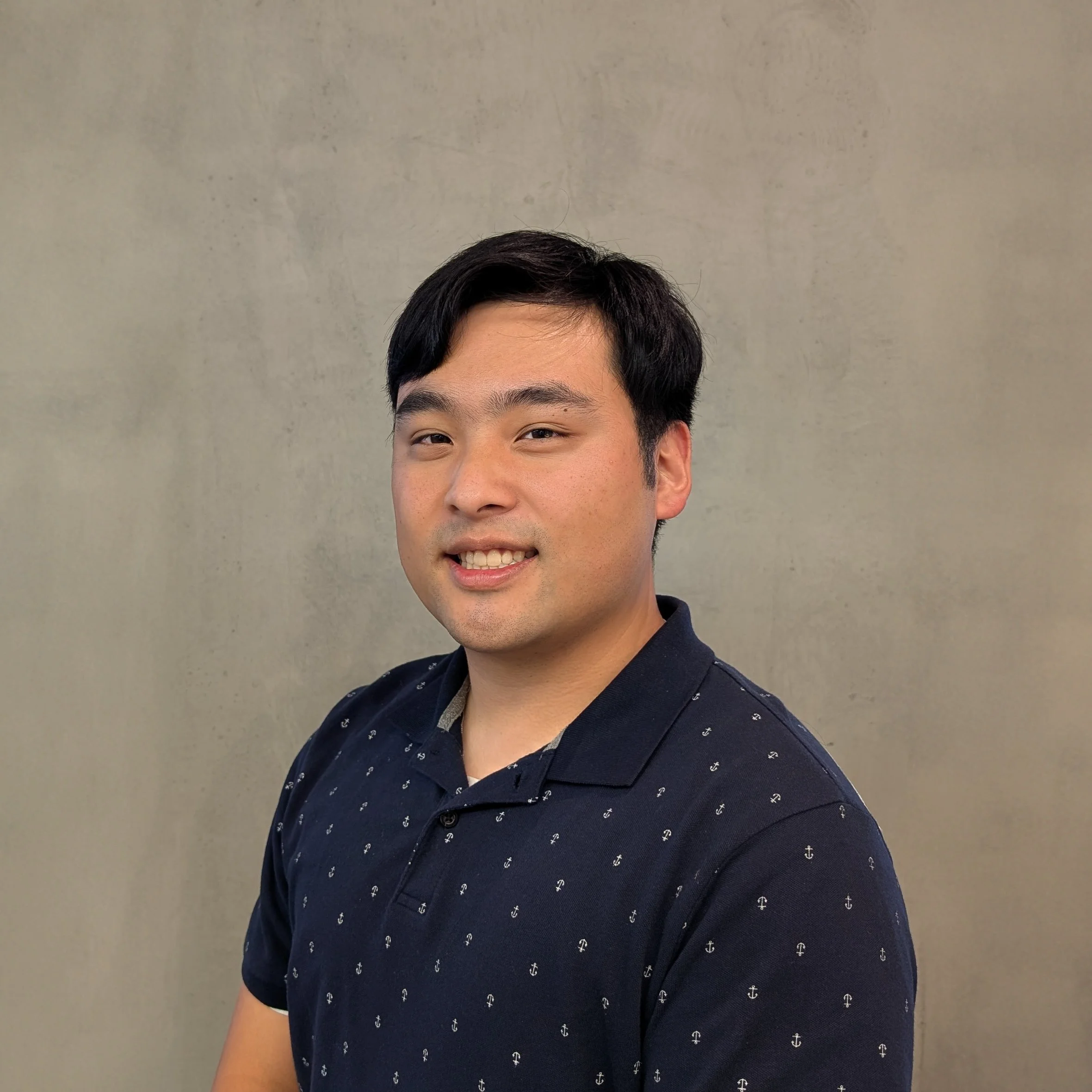 Headshot of Peter Kim, Stormwater Engineer-In-Training,, smiling against a concrete background.