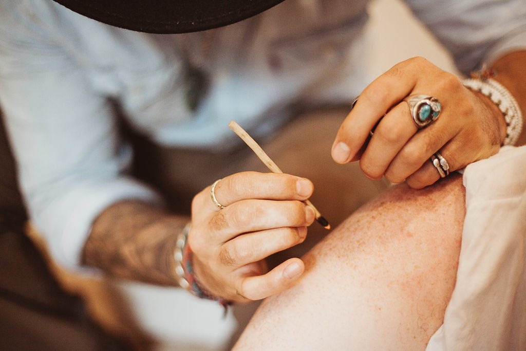 A person using a tamishi stick to burn small dots on the skin for applying Kambo.
