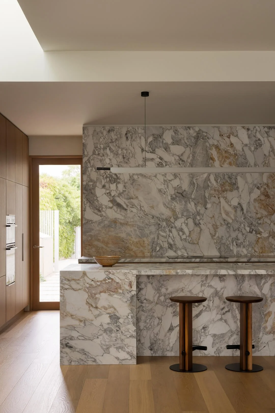 Modern kitchen elevation at Silver House featuring a monolithic Kalana natural stone island and rear garden views.