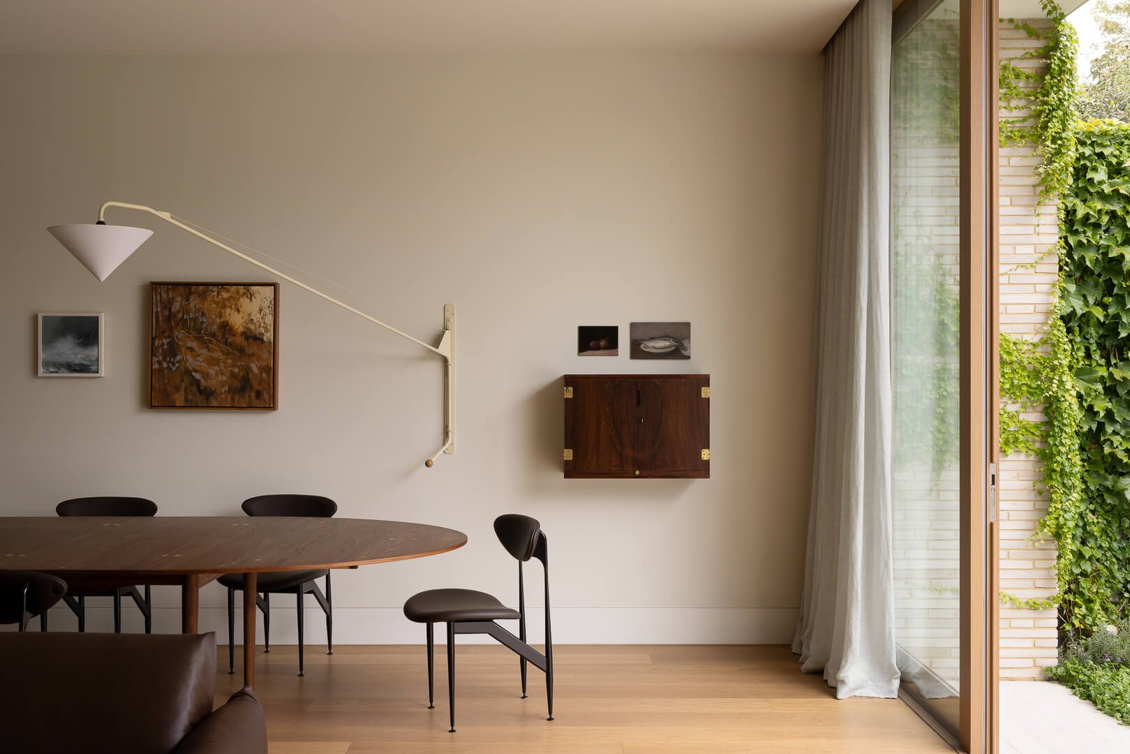 Modern dining room at Silver House featuring the House of Finn Juhl Silver Table, sculptural chairs, and narrow-format brickwork views.