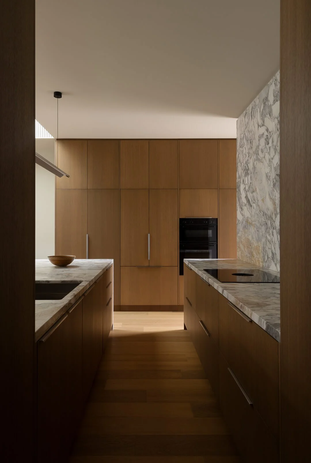 Modern kitchen at Silver House featuring warm timber joinery and Queensland-quarried Kalana natural stone benchtops.