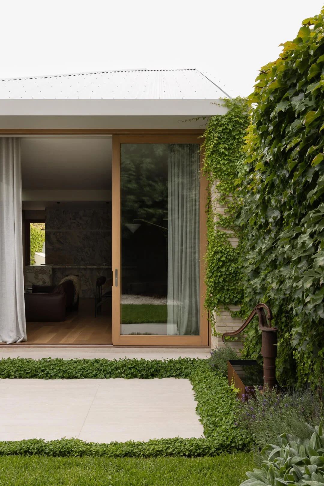 Architectural framing: View into the Silver House living area through timber-framed sliding doors by By Mysa.