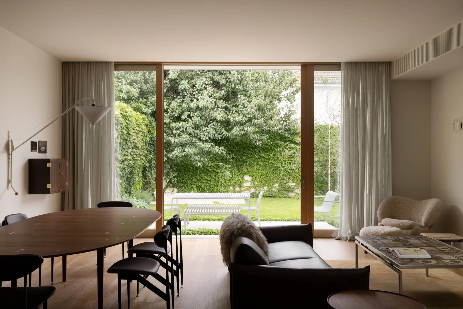 Open-plan living at Silver House featuring the House of Finn Juhl Sheepskin Pelican Chair and Silver Table with garden views.