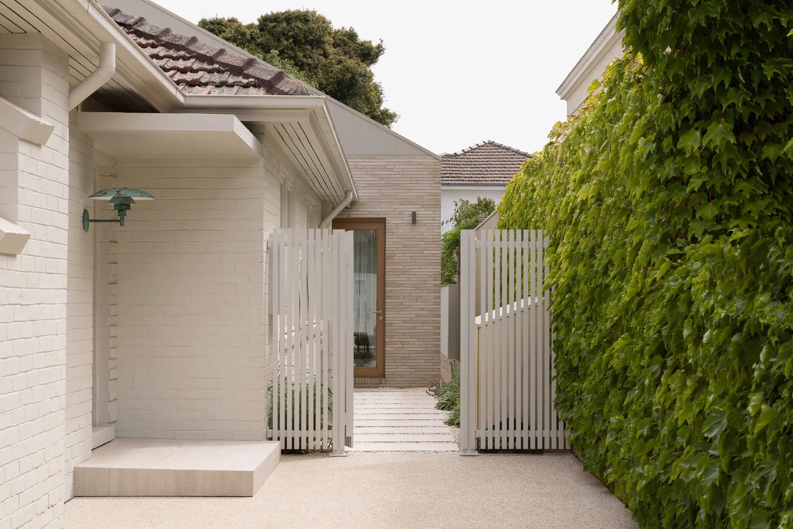 Modern garden path with pavers leading to the contemporary masonry extension of Silver House by By Mysa.