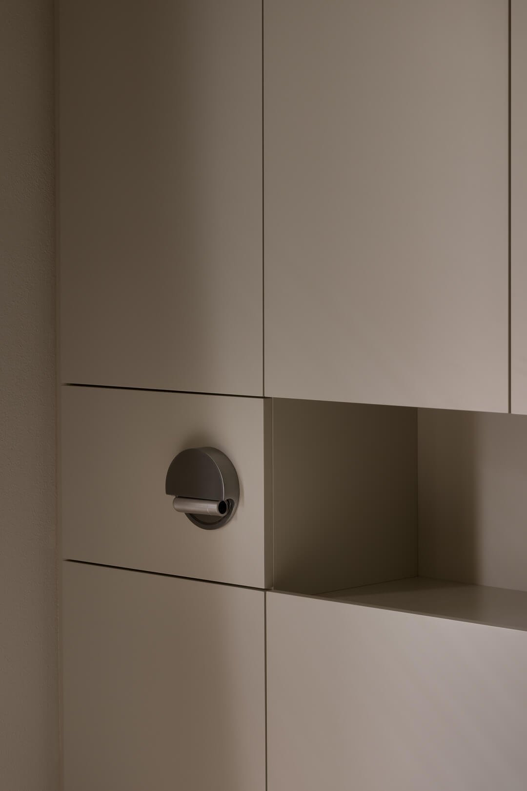 Macro detail of custom matte joinery with integrated shelving and a contemporary semi-circular wall light at Silver House.