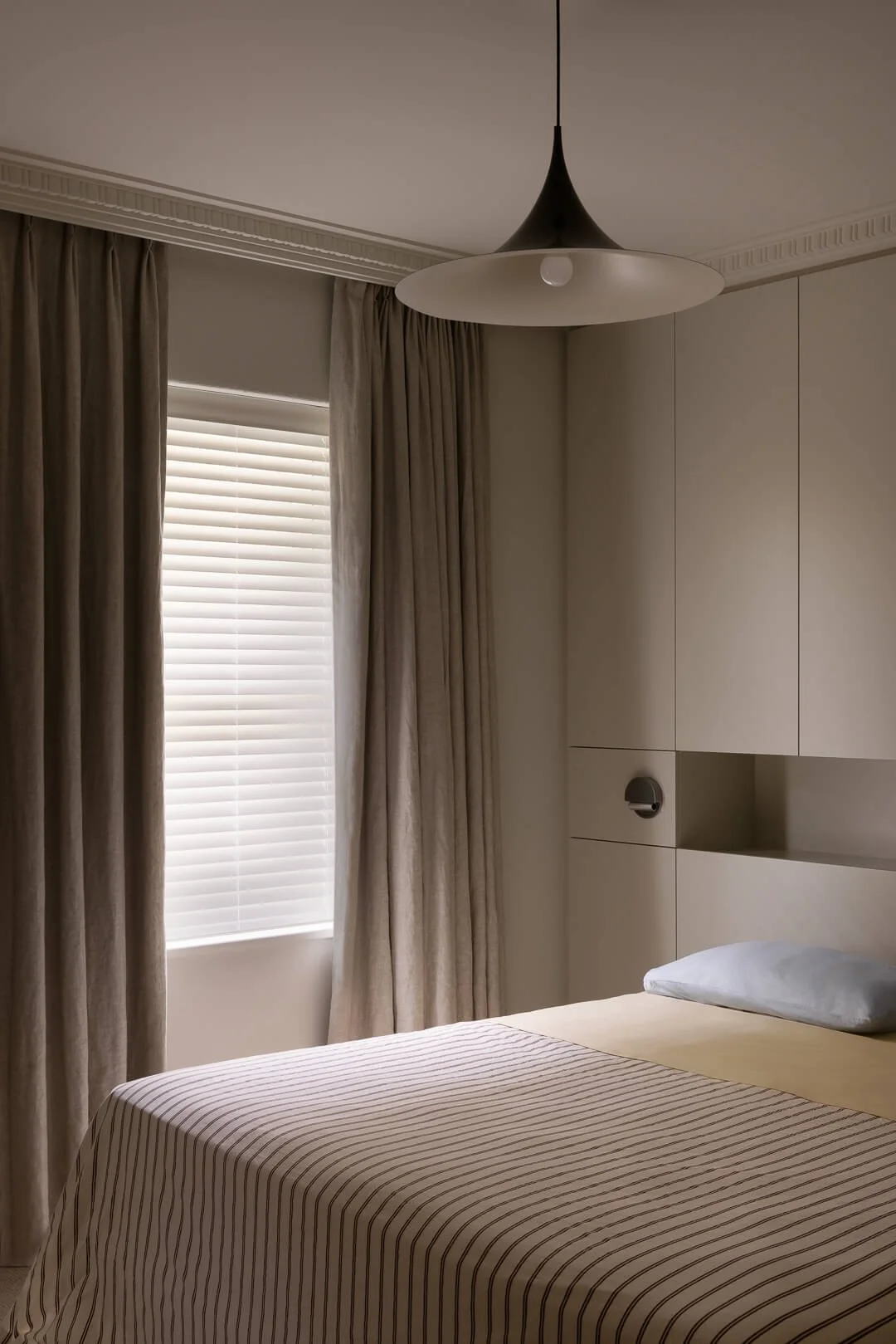 Minimalist bedroom at Silver House featuring custom joinery, linen curtains, and a sculptural designer pendant light.
