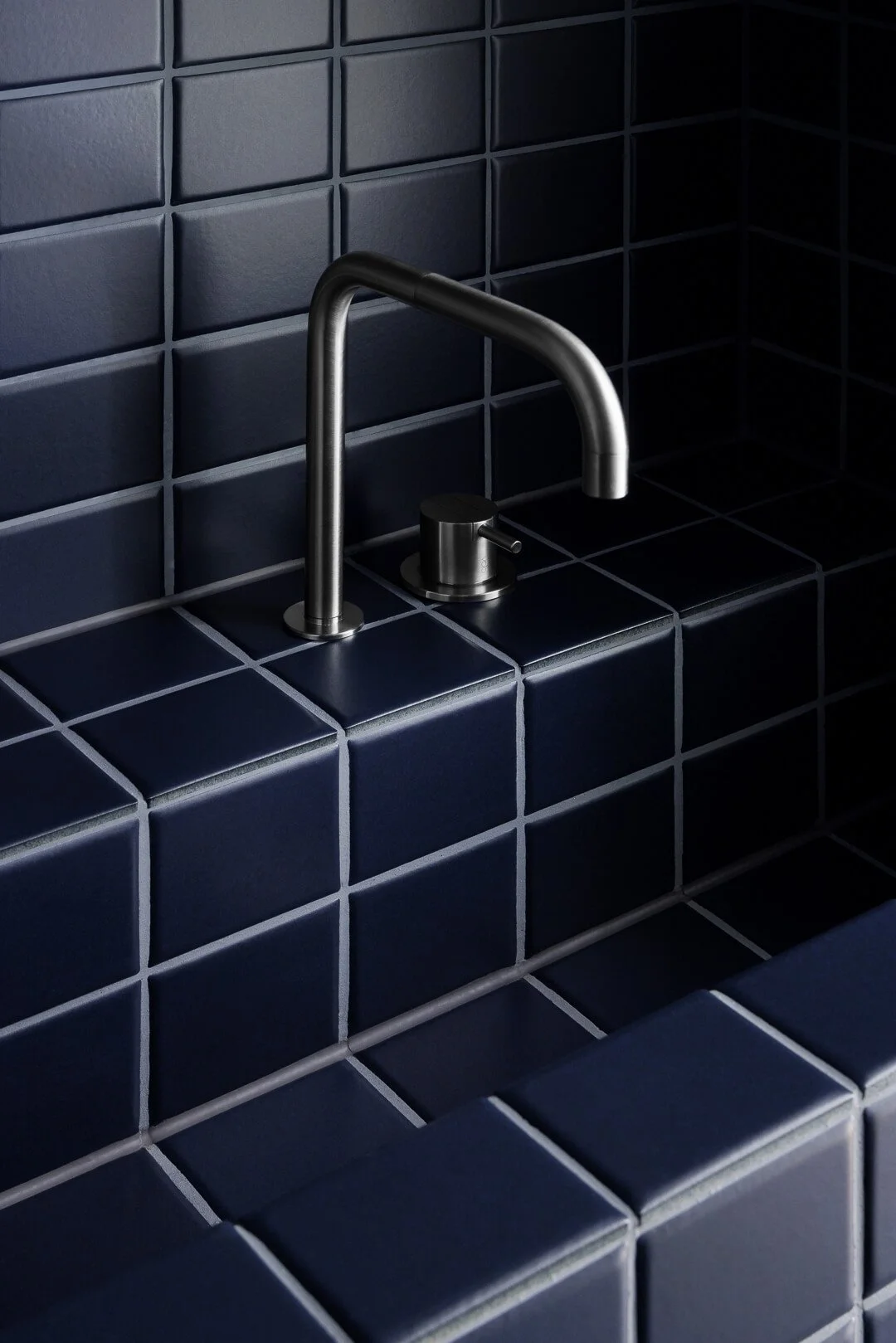 Minimalist Vola brushed metal tapware installed over navy blue square tiles at Silver House by By Mysa.