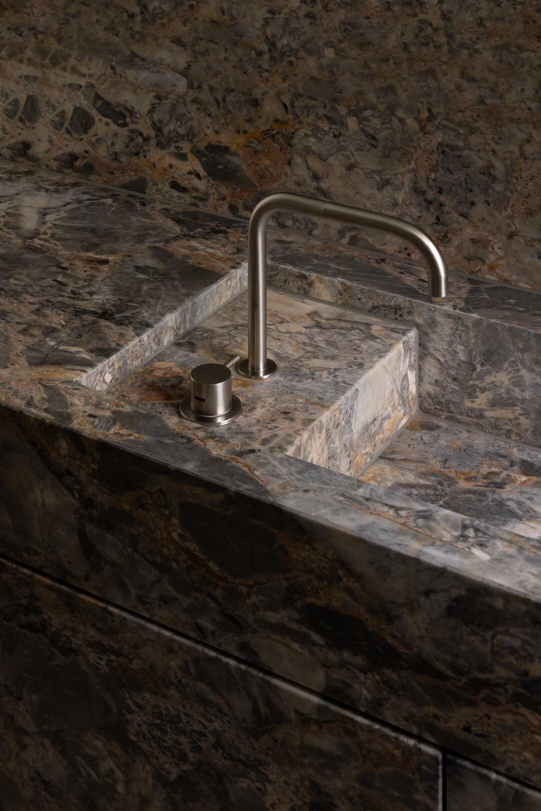 Detail of an integrated natural stone sink and brushed nickel tapware at Silver House by By Mysa.