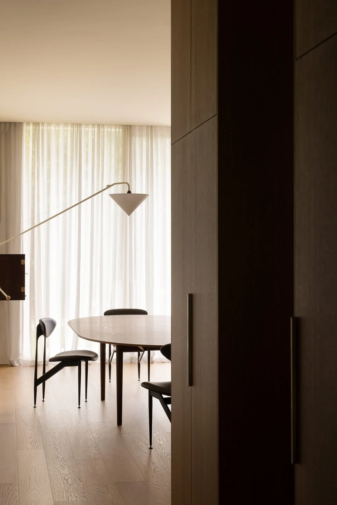 Mid-century Danish dining area featuring the House of Finn Juhl Silver Table and black chairs against sheer linen curtains at Silver House.