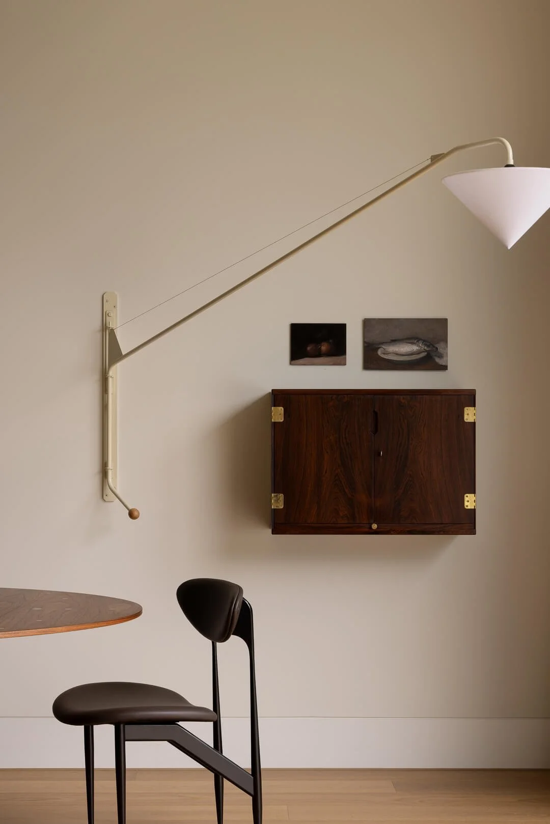 Detail of sculptural dining furniture, a vintage swing arm wall lamp, and a timber wall cabinet at Silver House.