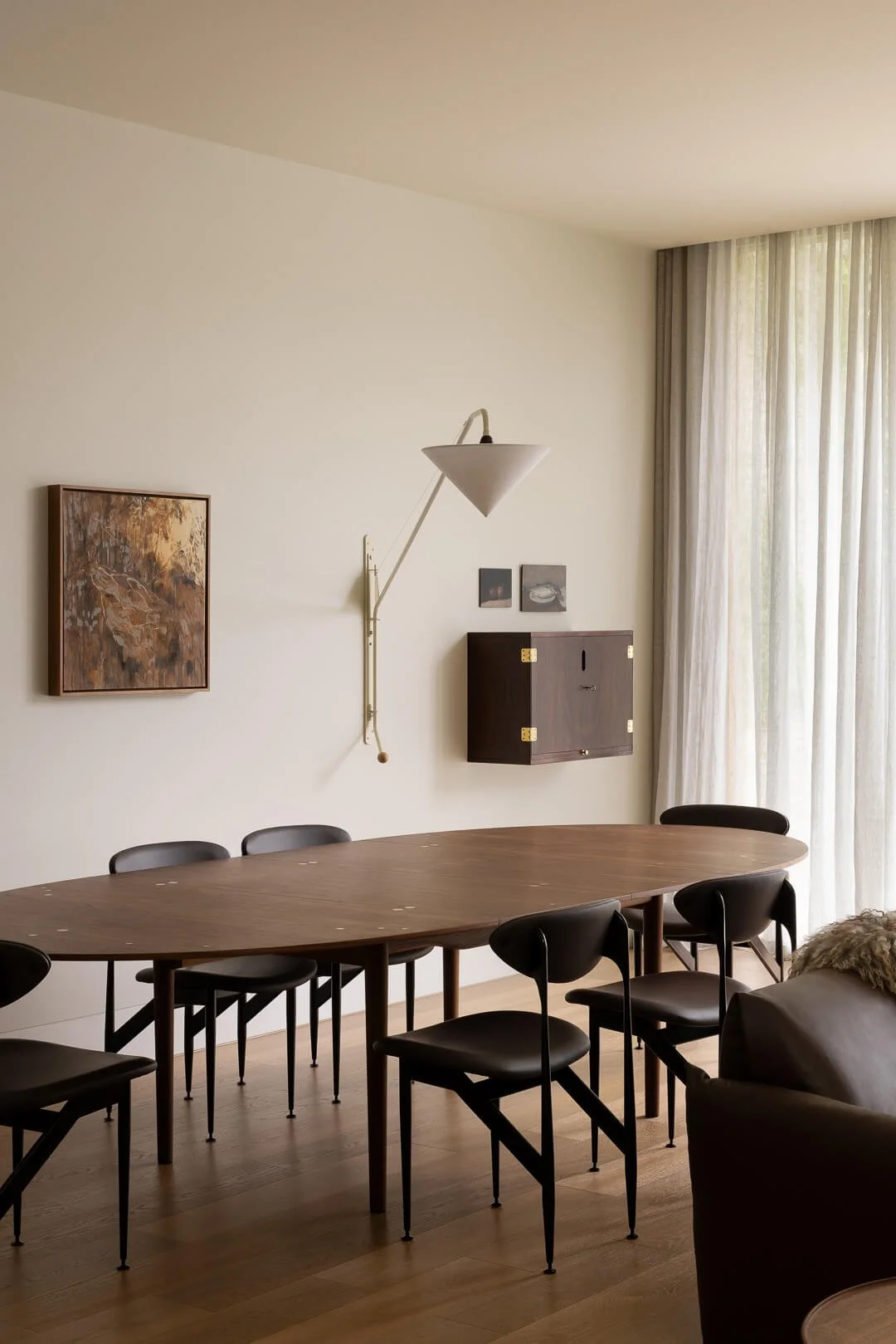 Curated dining room at Silver House featuring the House of Finn Juhl Silver Table, sculptural black chairs, and mid-century wall-mounted cabinetry.