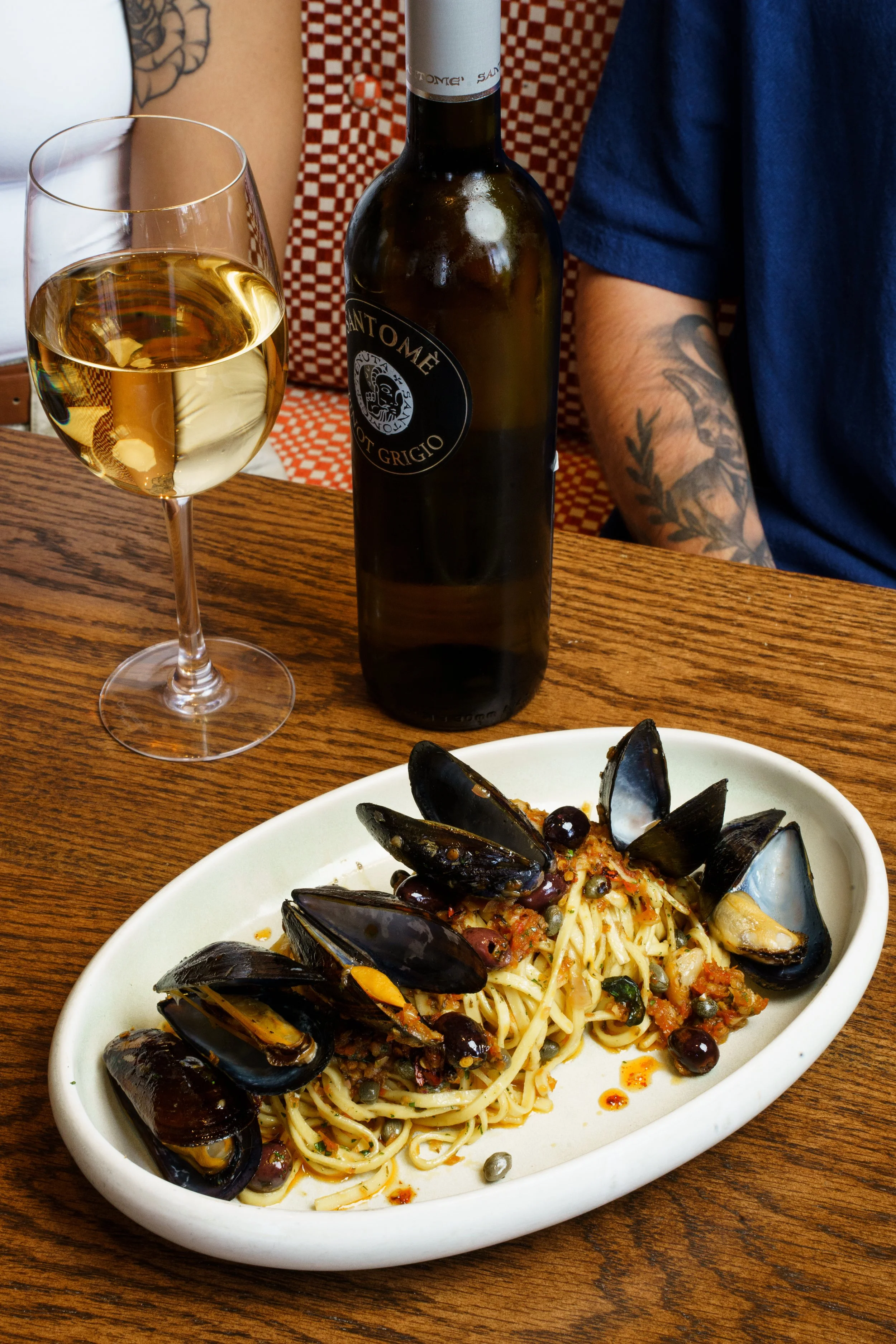 A plate of clam pasta and a bottle of wine