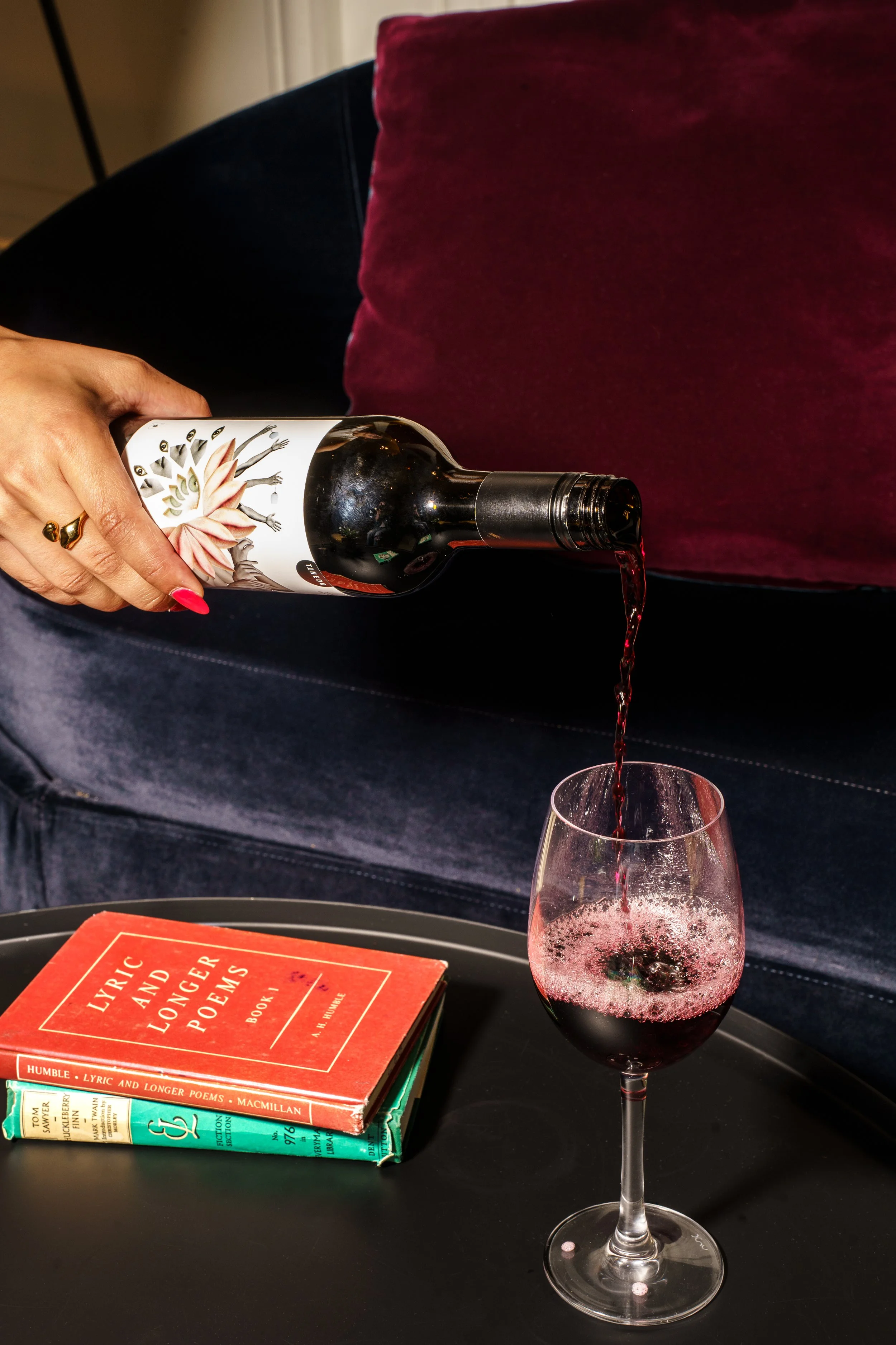 A manicured hand pouring a glass of wine.
