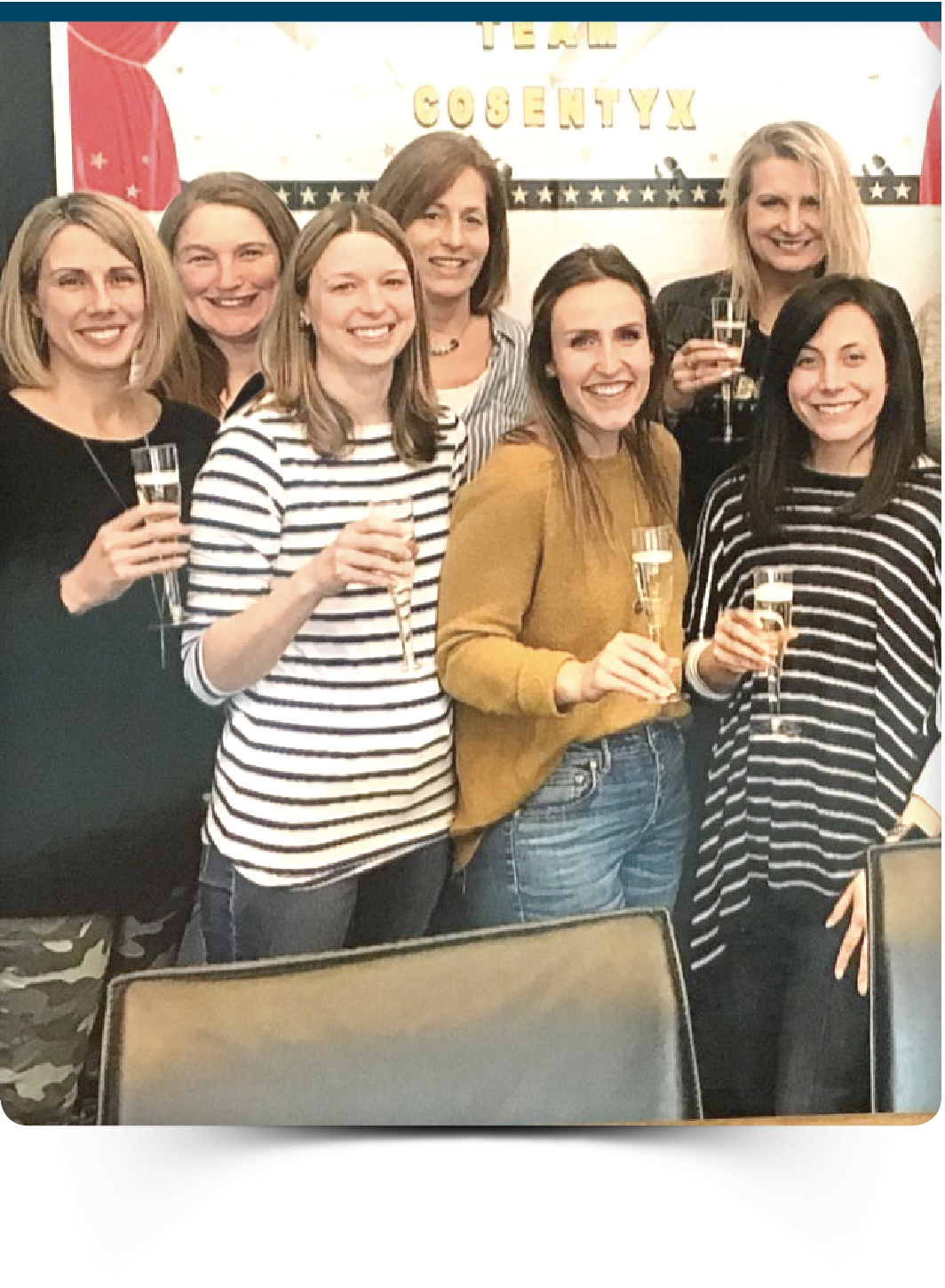 Group of women holding champagne glasses in front of a "Team Cosentyx" banner.