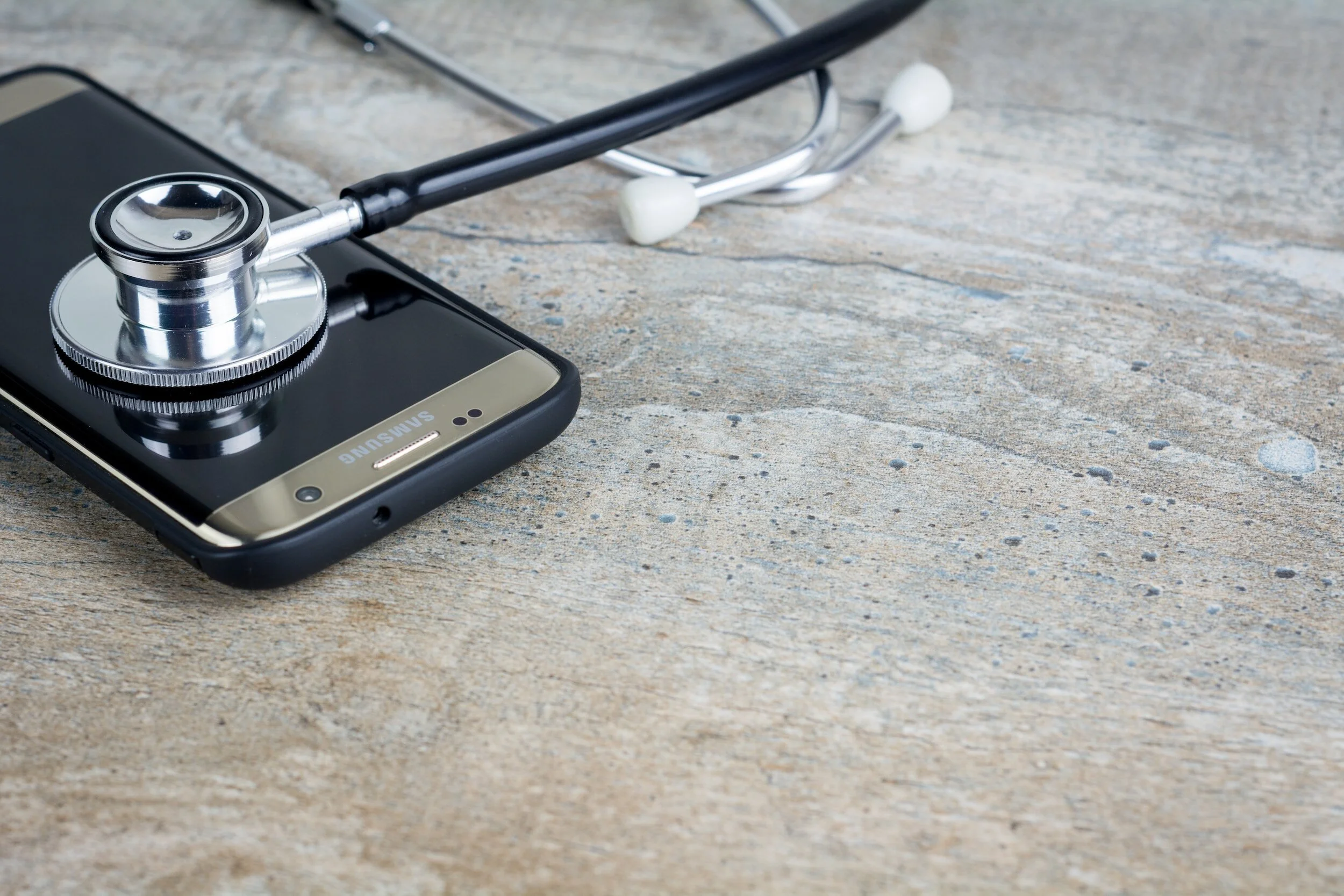 Medical Copywriter's phone on a wooden desk with stethoscope