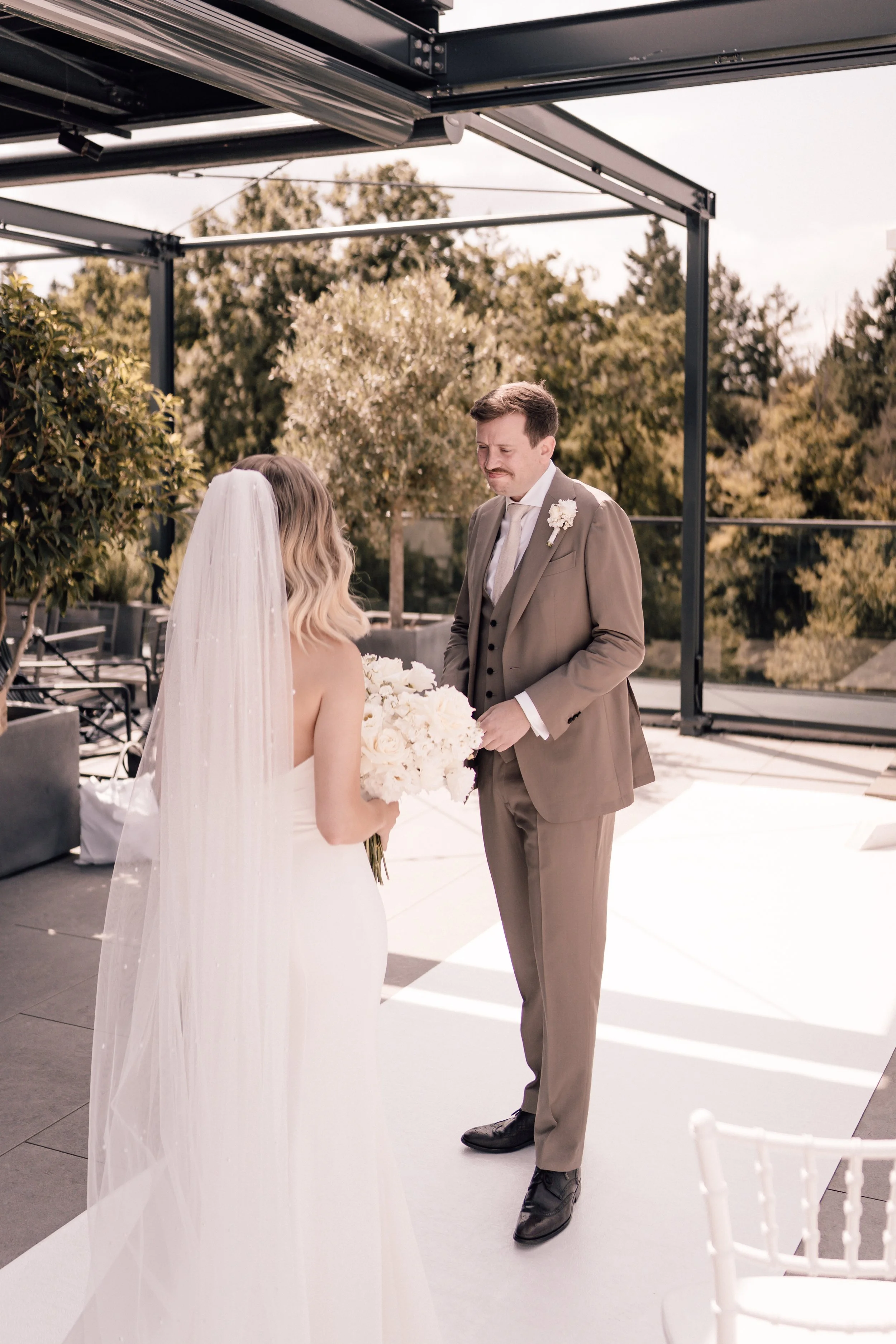 Braut und Bräutigam während ihrer standesamtlichen Trauung im Freien, die Braut hält einen weißen Blumenstrauß, beide in formeller Kleidung, mit einem Blick auf die Natur im Hintergrund. Sven Goos Fotografie