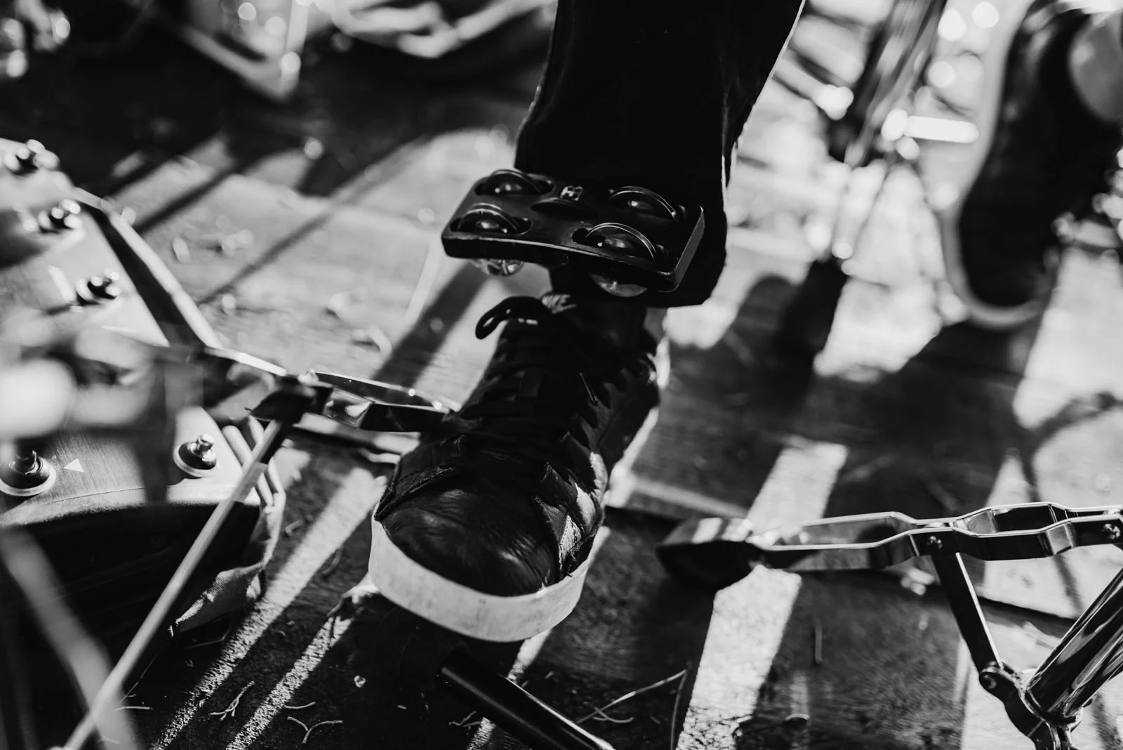 Dettaglio di un pedale di una bicicletta e di una scarpa sportiva, visibile una parte del telaio e le pedane, in un'ambientazione all'aperto.