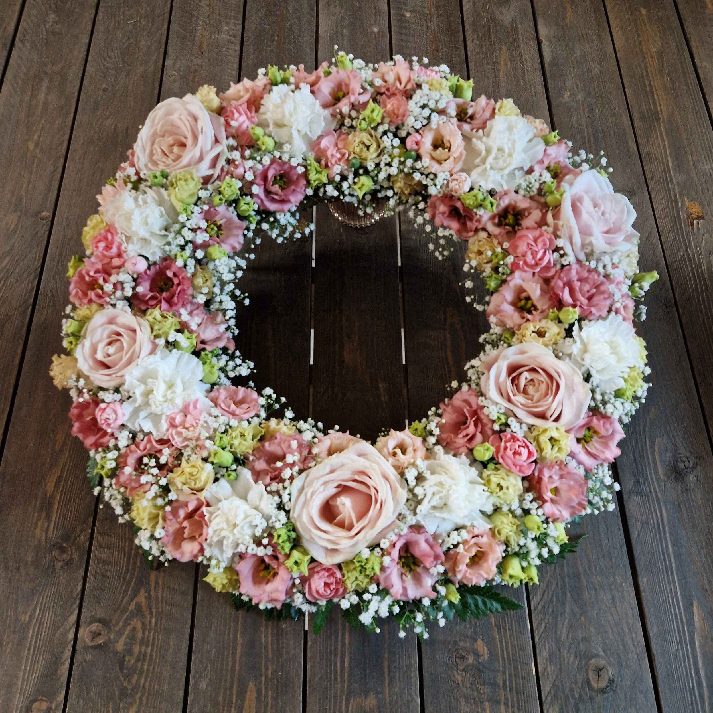 En krans till begravning i rosa och ljusa toner.