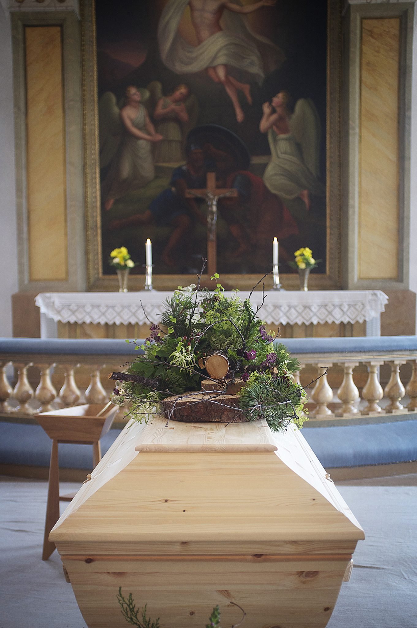 Dekorerad kista med blommor i kyrkan vid begravning.