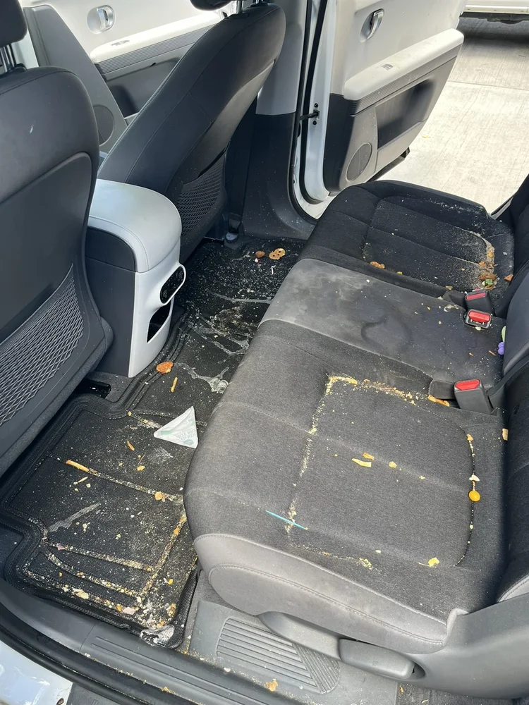 Back seat covered in food and spills before detailing