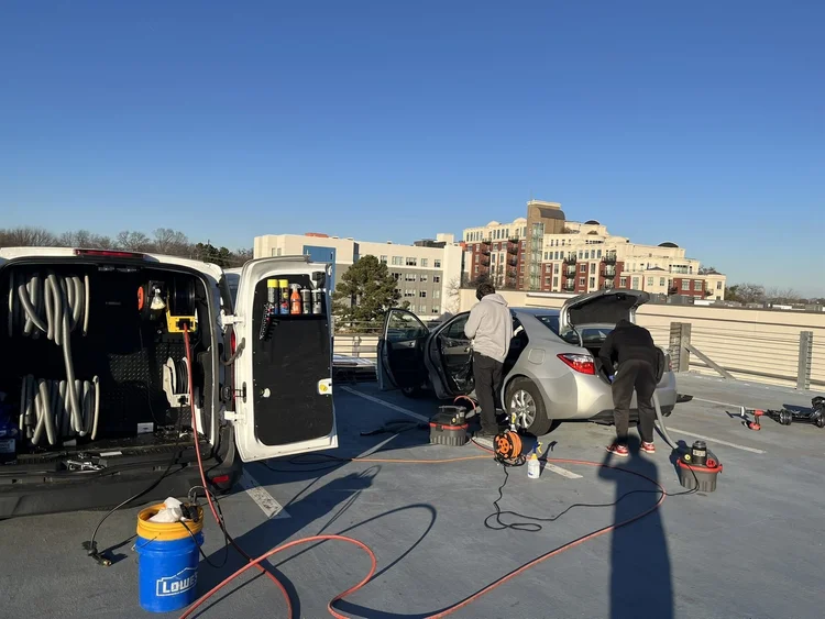 Oak City team detailing a car on a downtown Raleigh rooftop, van fully equipped