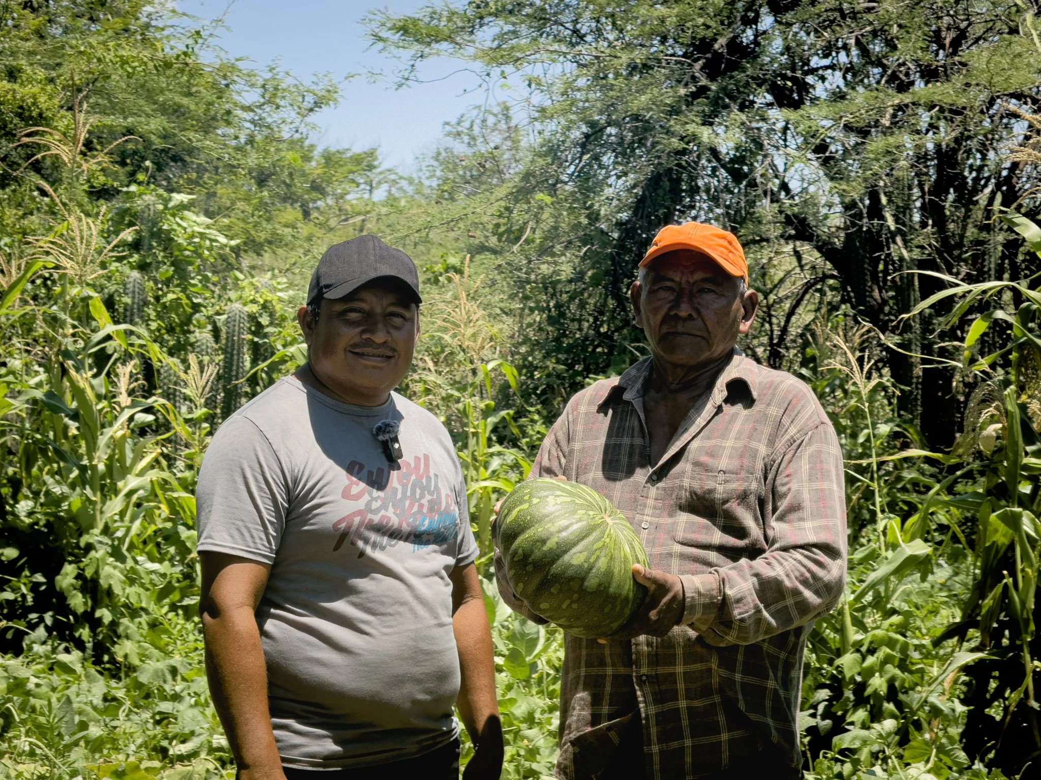 Dos hombres en un campo de cultivo sosteniendo una sandía grande.