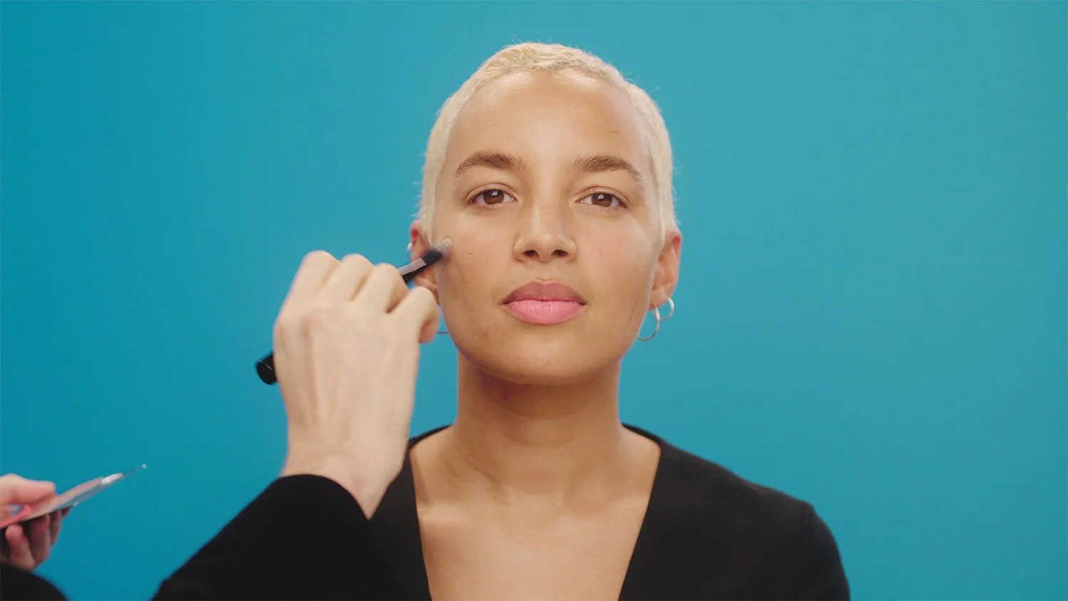 girl with short blonde hair getting makeup applied to her face