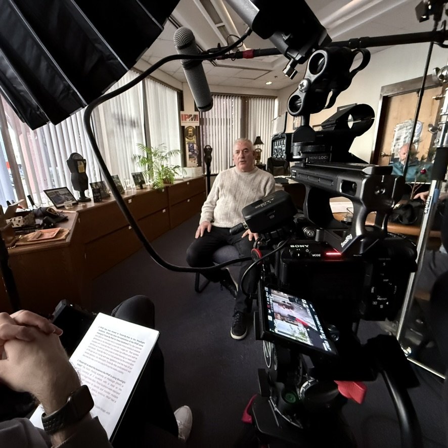 Man sitting in a professional recording setup with camera and microphones.