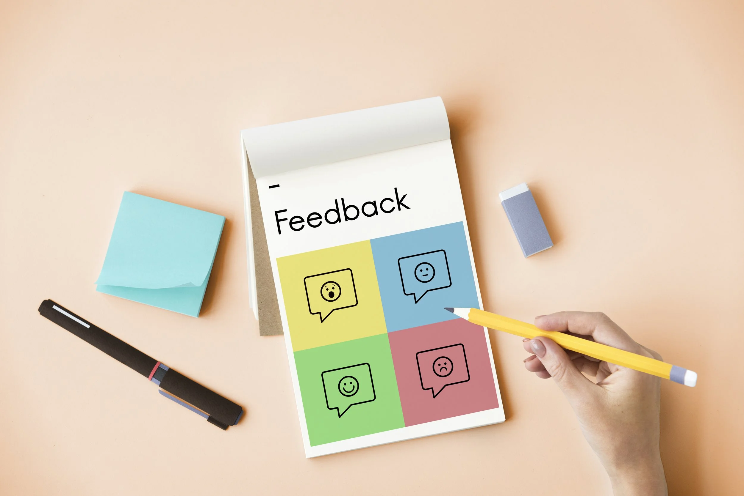 Feuille de papier avec le mot 'Feedback' au sommet, divisé en quatre sections colorées avec des icônes de visages exprimant diverses émotions.